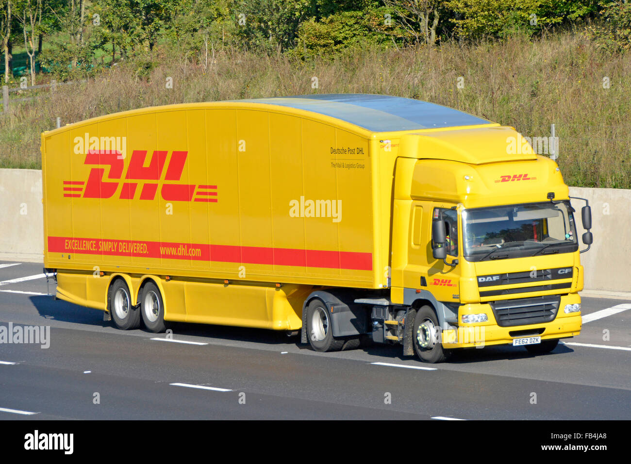 Vista laterale e frontale carrozzeria sagomata hgv Deutsche Post DHL consegna camion e conducente con logo sul rimorchio autostrada Inghilterra UK Foto Stock