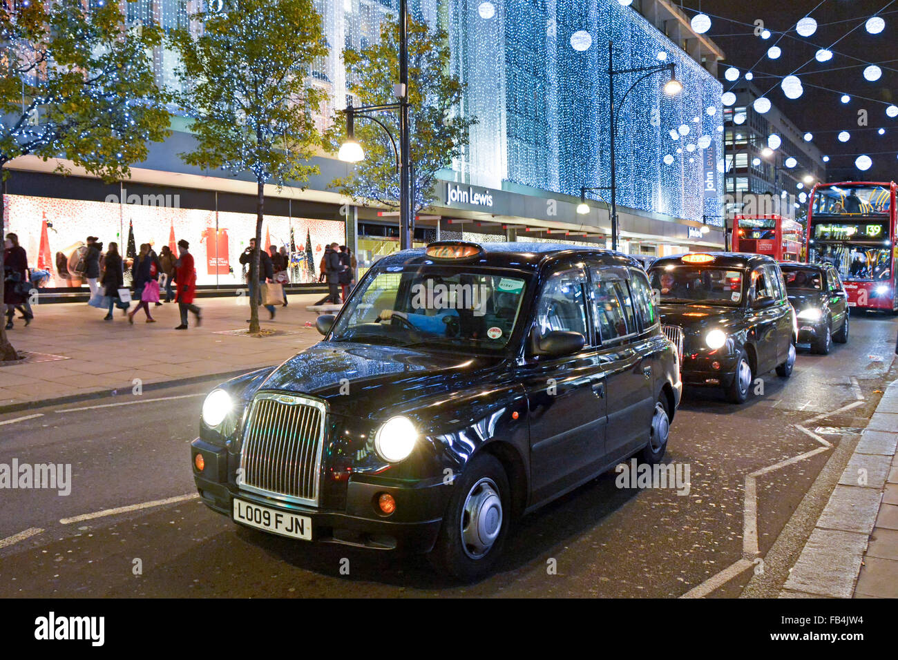 Luci di Natale addobbi Londra taxi autista in attesa in coda al traffico fuori del John Lewis Department Store edificio a Oxford Street West End Regno Unito Foto Stock