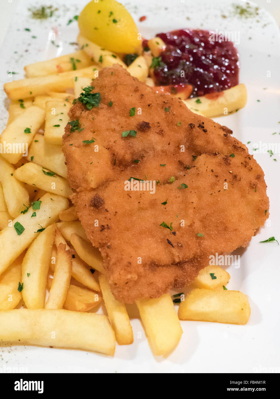 Carne impanata servita con patatine fritte, piatto tipico in Austria chiamato Wiener Schnitzel. Foto Stock