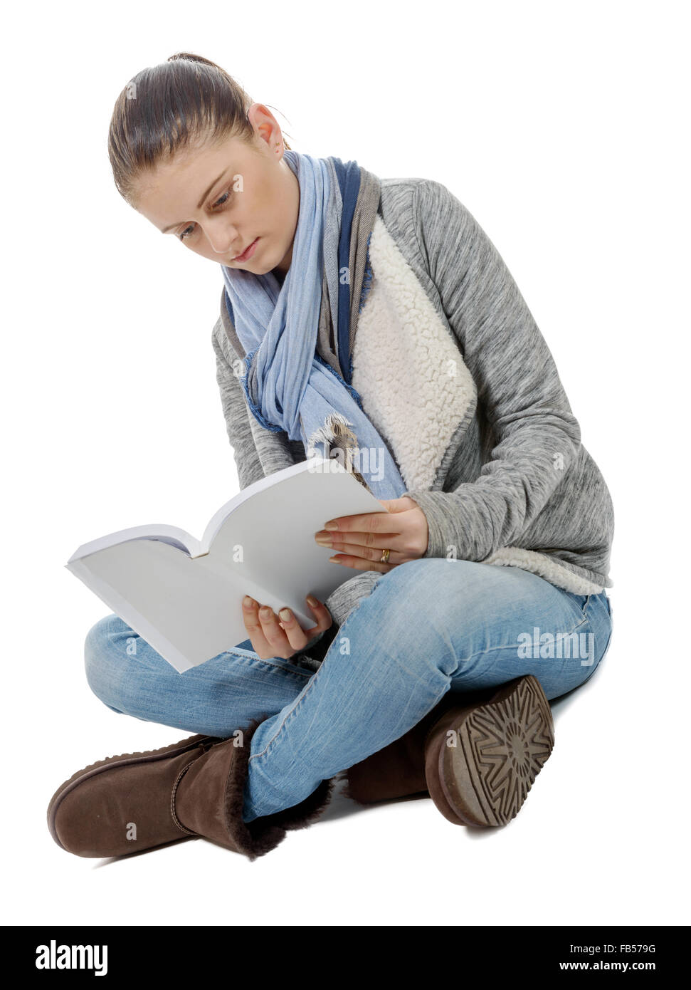 Una bella ragazza seduta con le gambe incrociate, la lettura di un libro su uno sfondo bianco Foto Stock