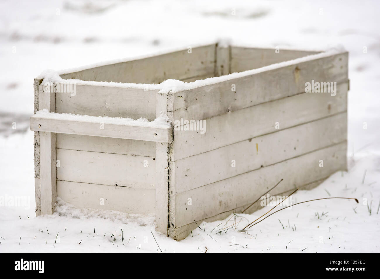 Un bianco aprire una scatola di legno in piedi nella neve. Messa a fuoco poco profonda su angolo anteriore. Foto Stock