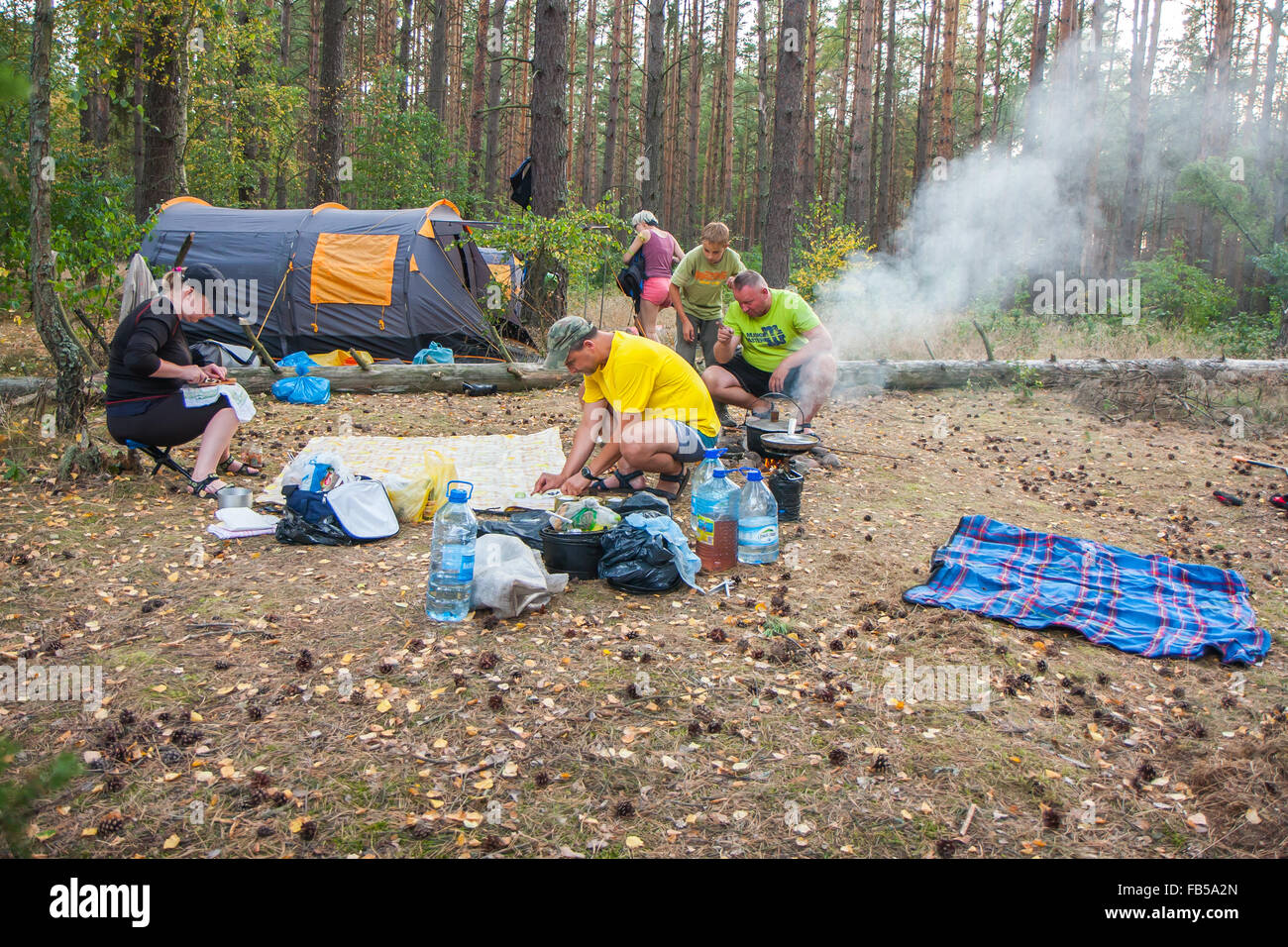 Fiume Plawa, Polonia - 26 agosto 2015: un gruppo di turisti impostare una tenda nel bosco e cucinare un pasto su un falò Foto Stock