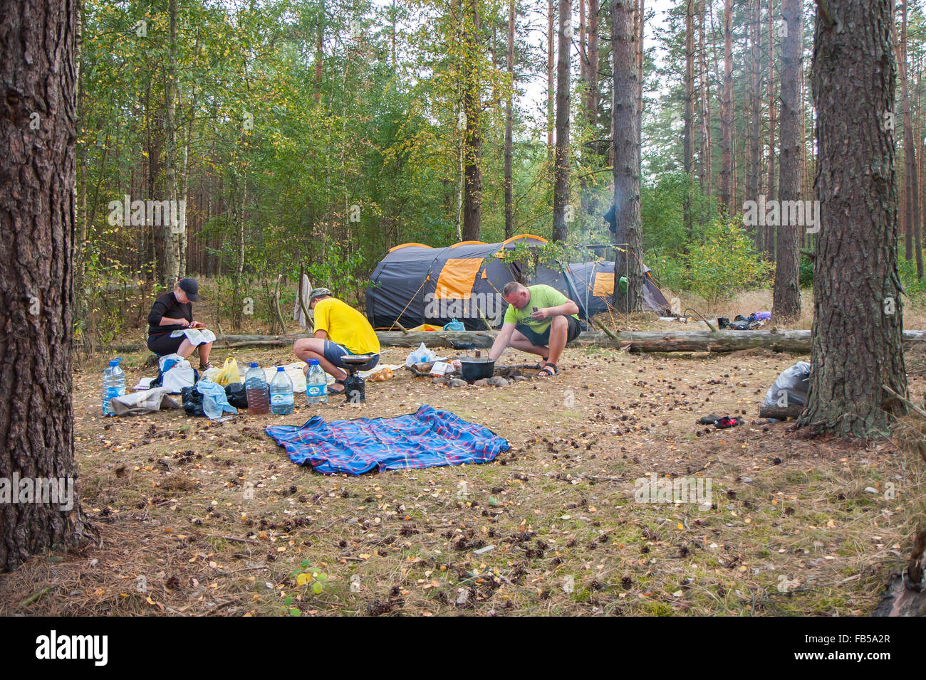 Fiume Plawa, Polonia - 26 agosto 2015: un gruppo di turisti impostare una tenda nel bosco e cucinare un pasto su un falò Foto Stock