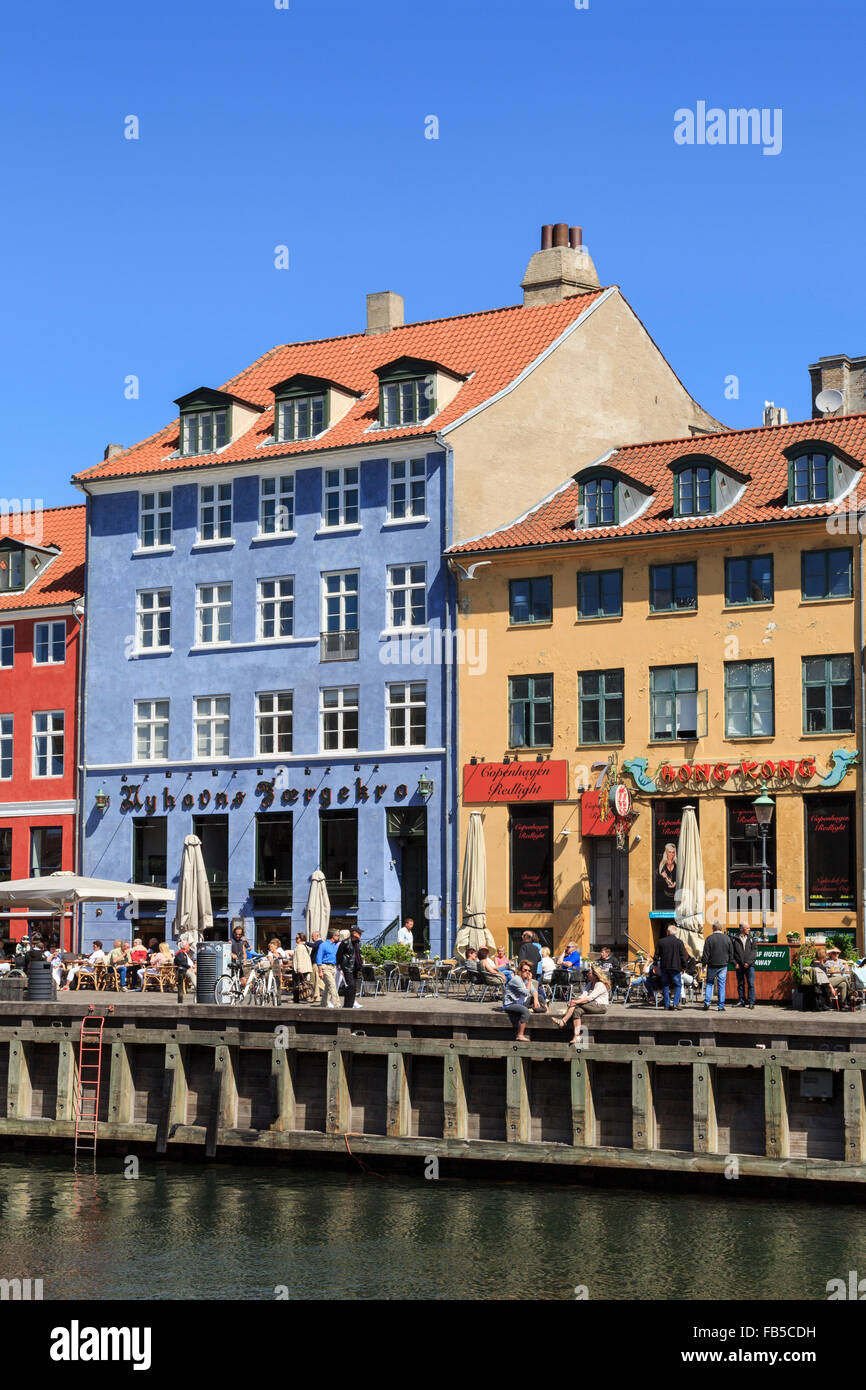 Persone relax su canal quay con i suoi edifici colorati sul lungomare in estate. Nyhavn, Copenaghen, Zelanda, Danimarca, Europa Foto Stock
