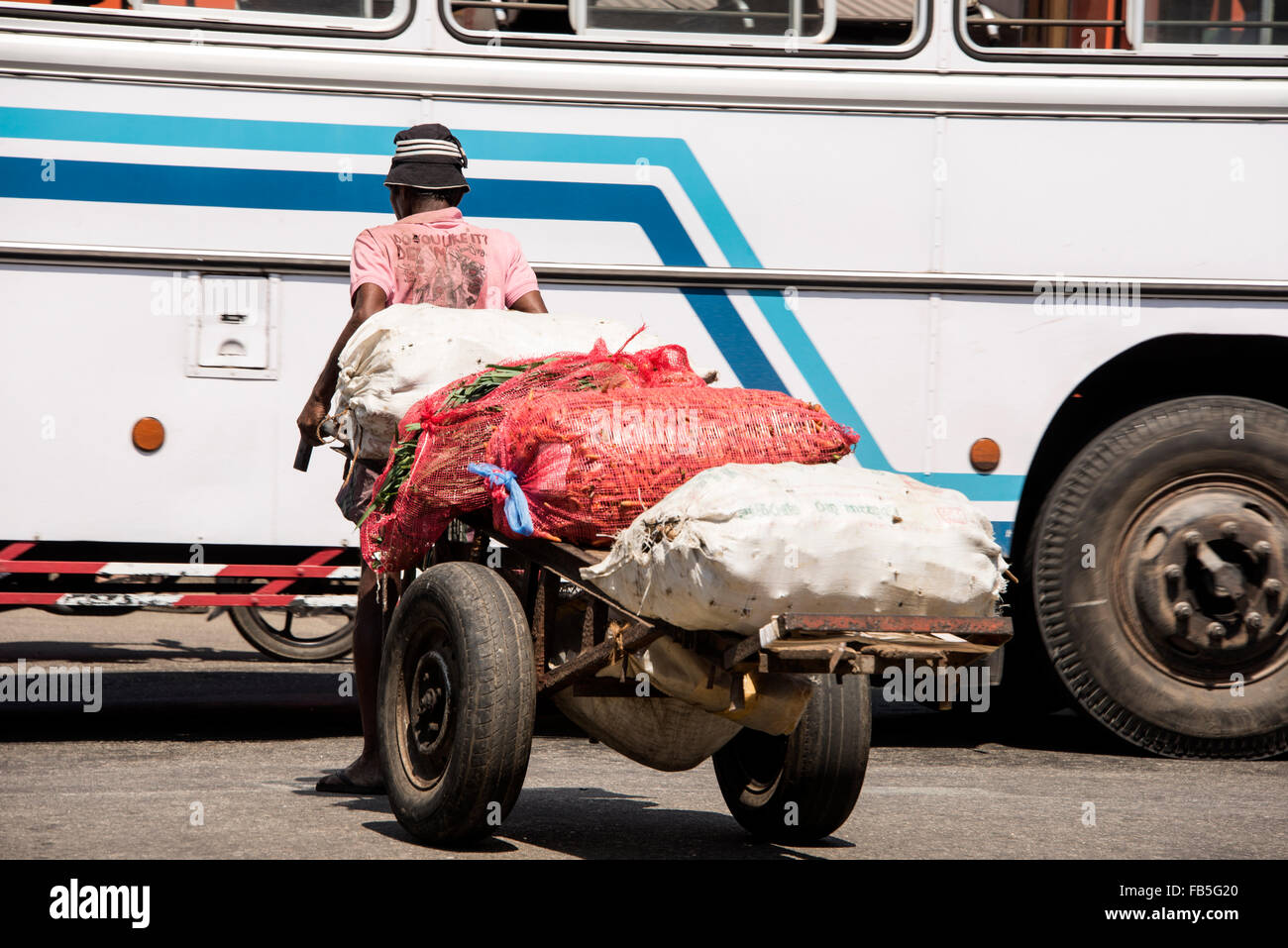 Un uomo carriola che tira il suo carrello di verdure lungo una strada trafficata nel distretto di Pettah di Colombo, Sri Lanka Foto Stock