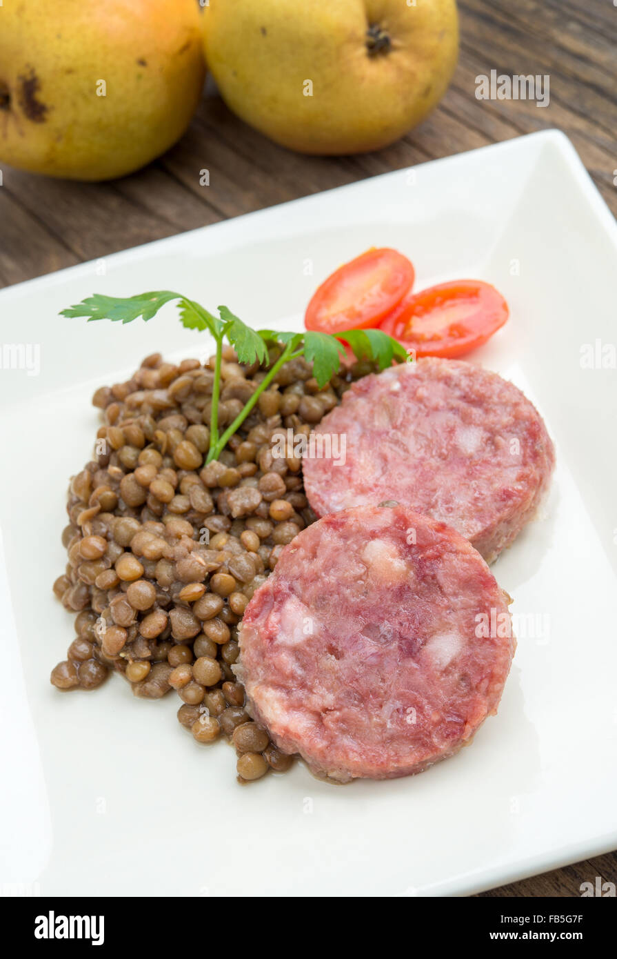 Piatto di lato di sausagecotechino e le lenticchie con il prezzemolo e il pomodoro sweet Foto Stock