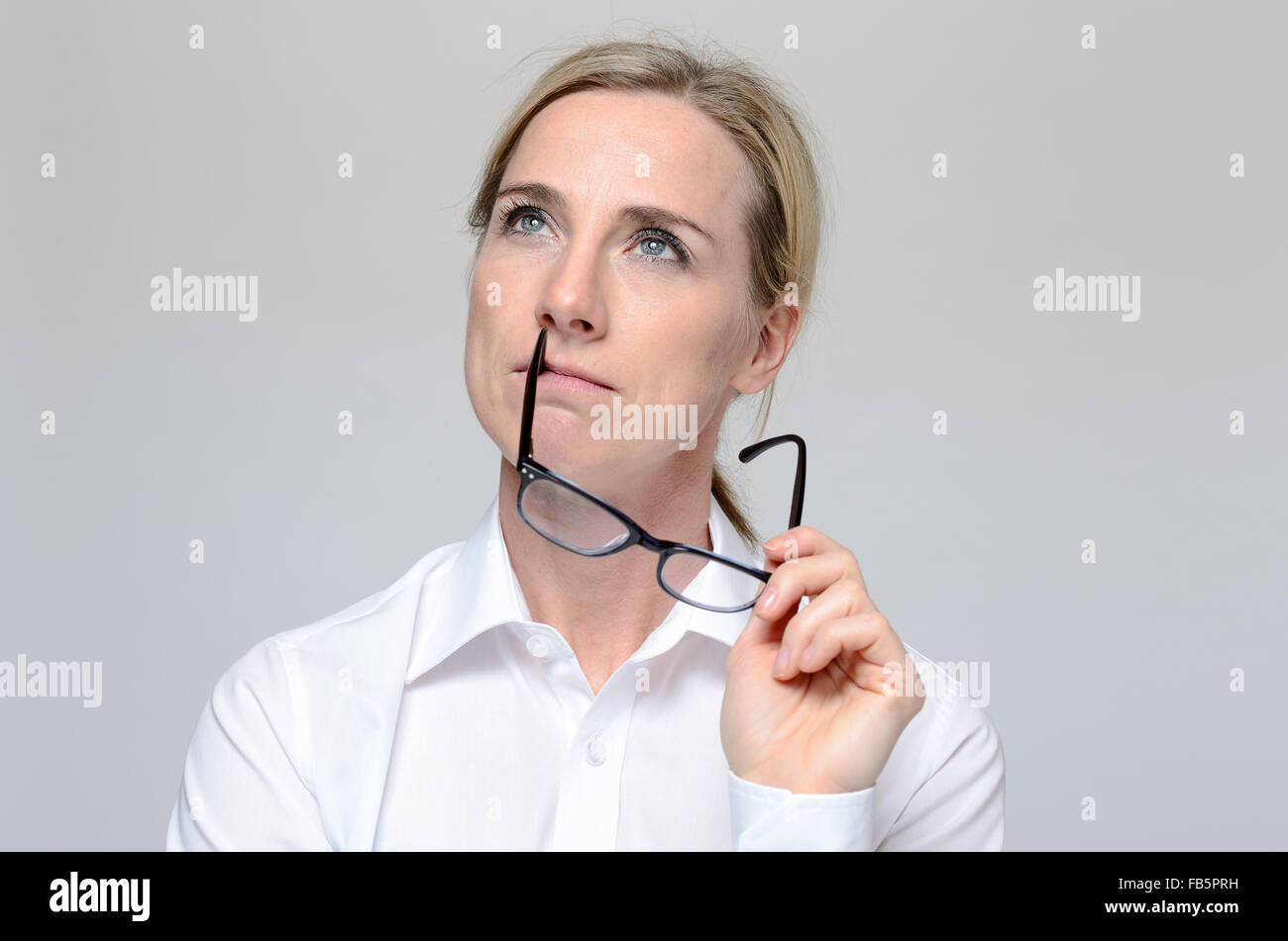 Considerato attraente imprenditrice guardando in aria con un espressione contemplativa con i suoi occhiali in mano, hea Foto Stock
