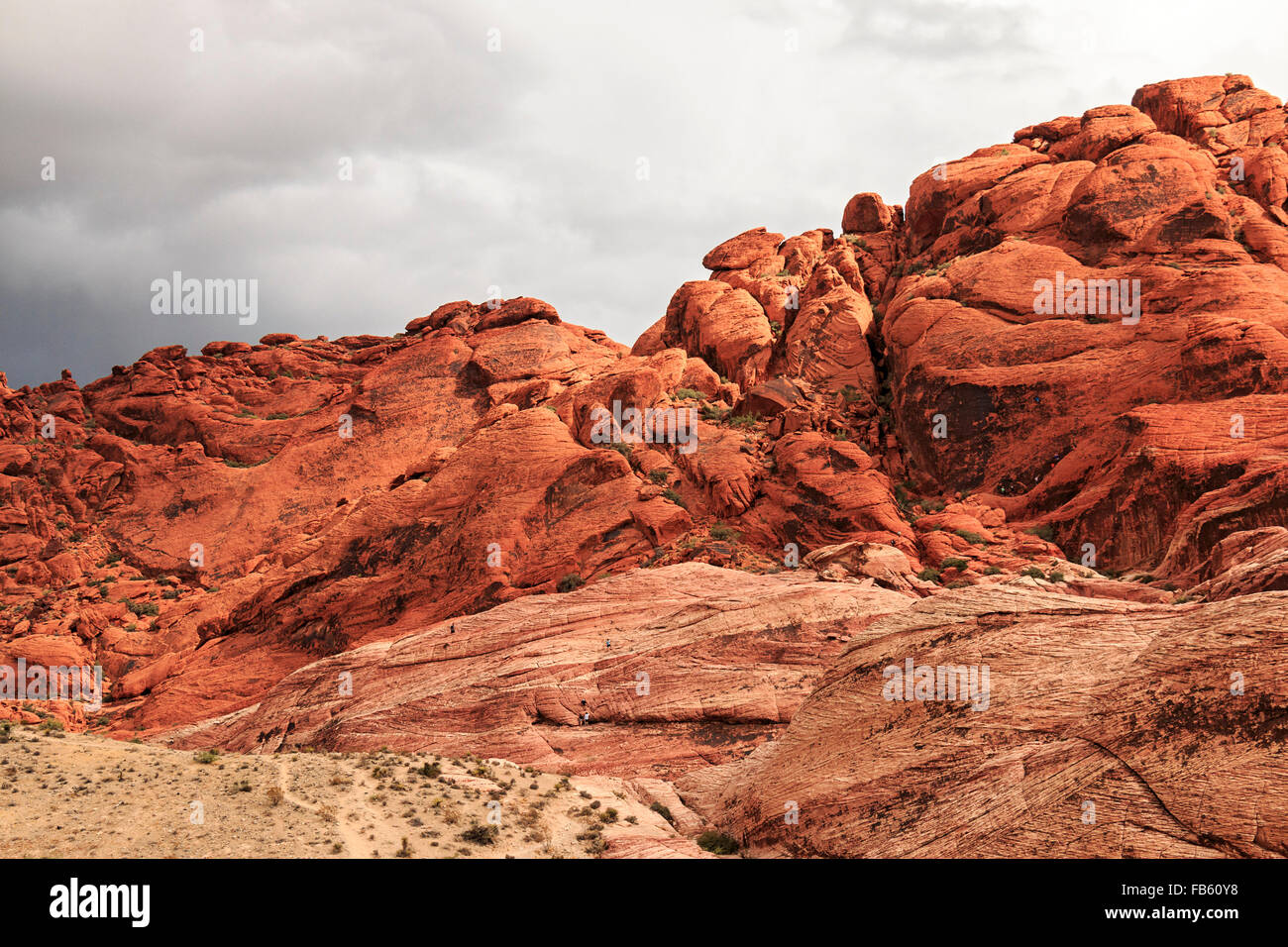 Gli scalatori arrampicarsi su e giù per le rocce come nuvole temporalesche chiudere in su il calicò Colline del Red Rock Canyon National Conservation Area Foto Stock