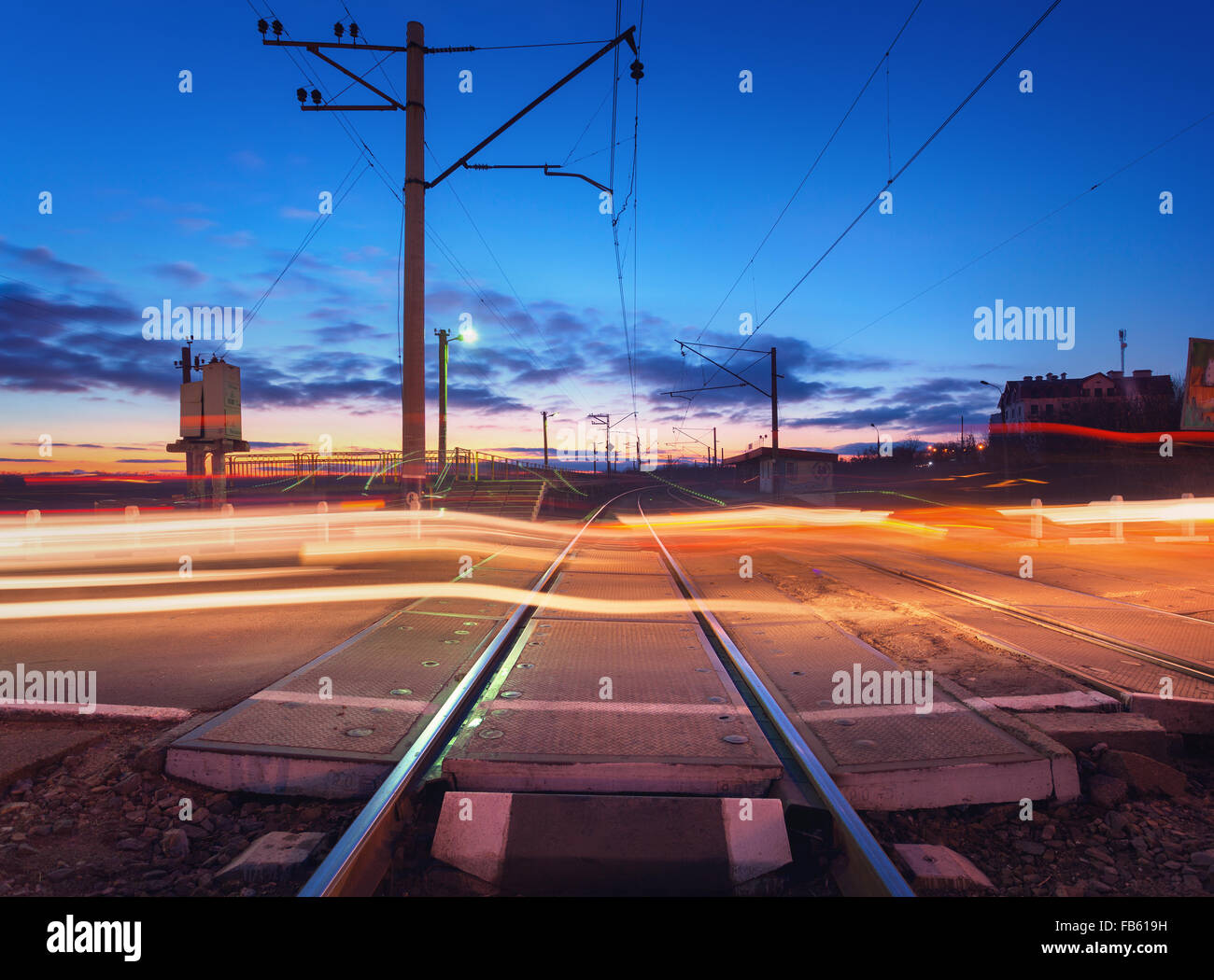 Attraversamento ferroviario con luci auto in movimento durante la notte. Foto Stock
