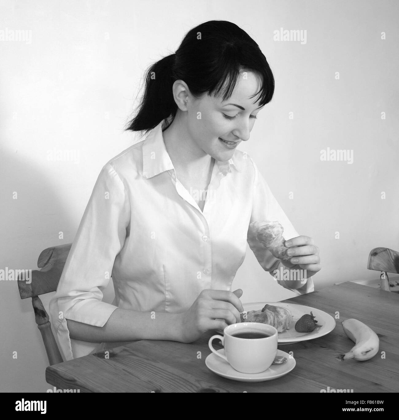 Piuttosto giovane donna caucasica a mangiare una sana colazione con un caffè. Foto Stock