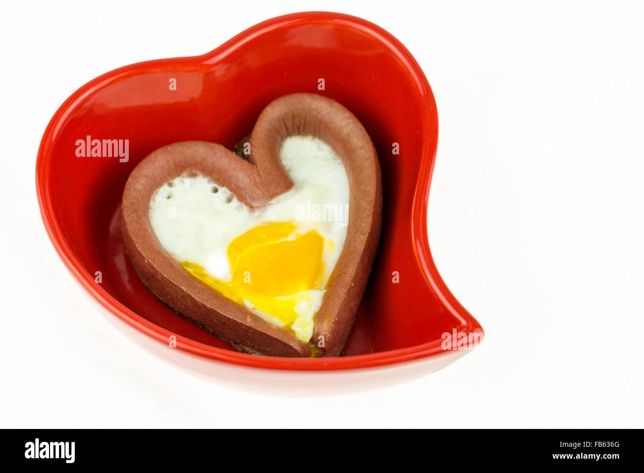 Uovo con una a forma di cuore le salsicce a cuore rosso-piastra sagomata isolata su sfondo bianco Foto Stock