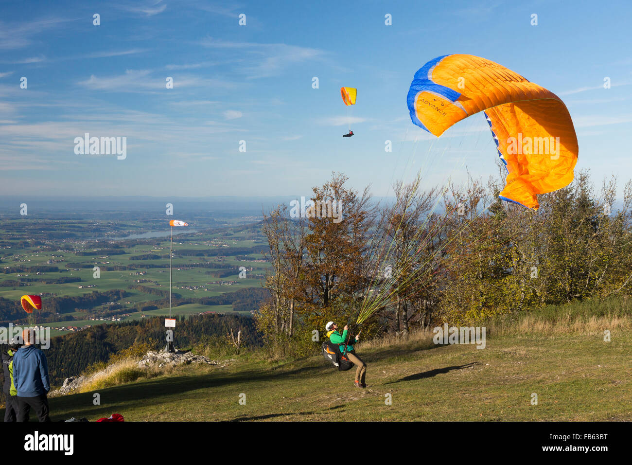 Un parapendio il tentativo di gonfiare la sua ala come egli tenta un lancio di retromarcia con forte vento contrario sul monte Gaisberg, Salisburgo Foto Stock