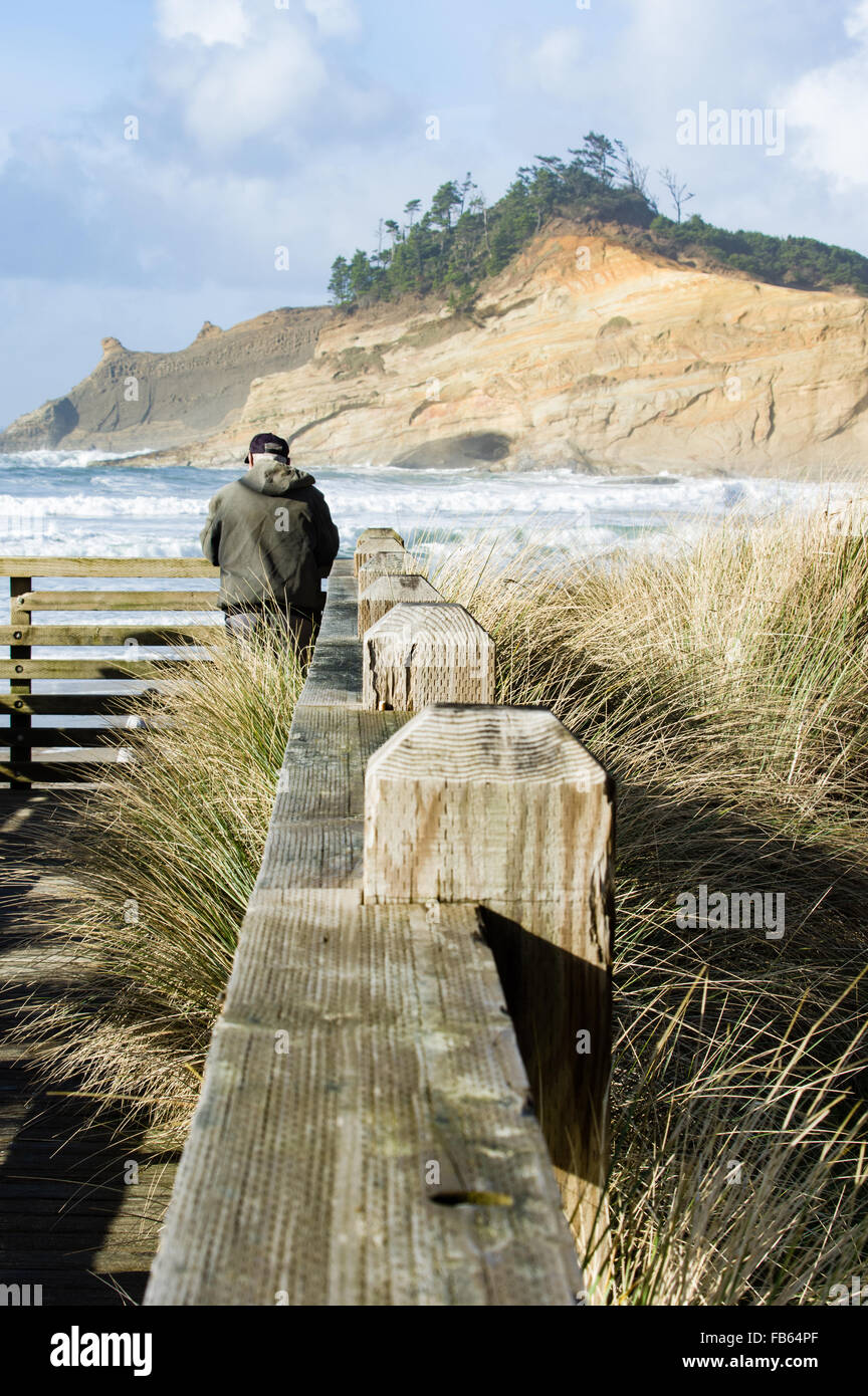 Un uomo orologi il surf sulla spiaggia da un si affacciano, Città del Pacifico, Oregon Foto Stock