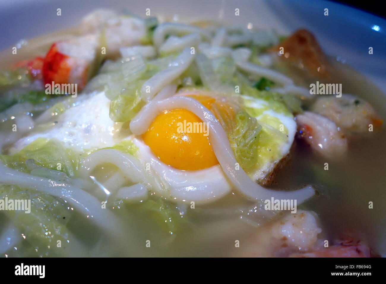 Una ciotola di Asian Udon noodle soup con frutti di mare, uova e verdure Foto Stock