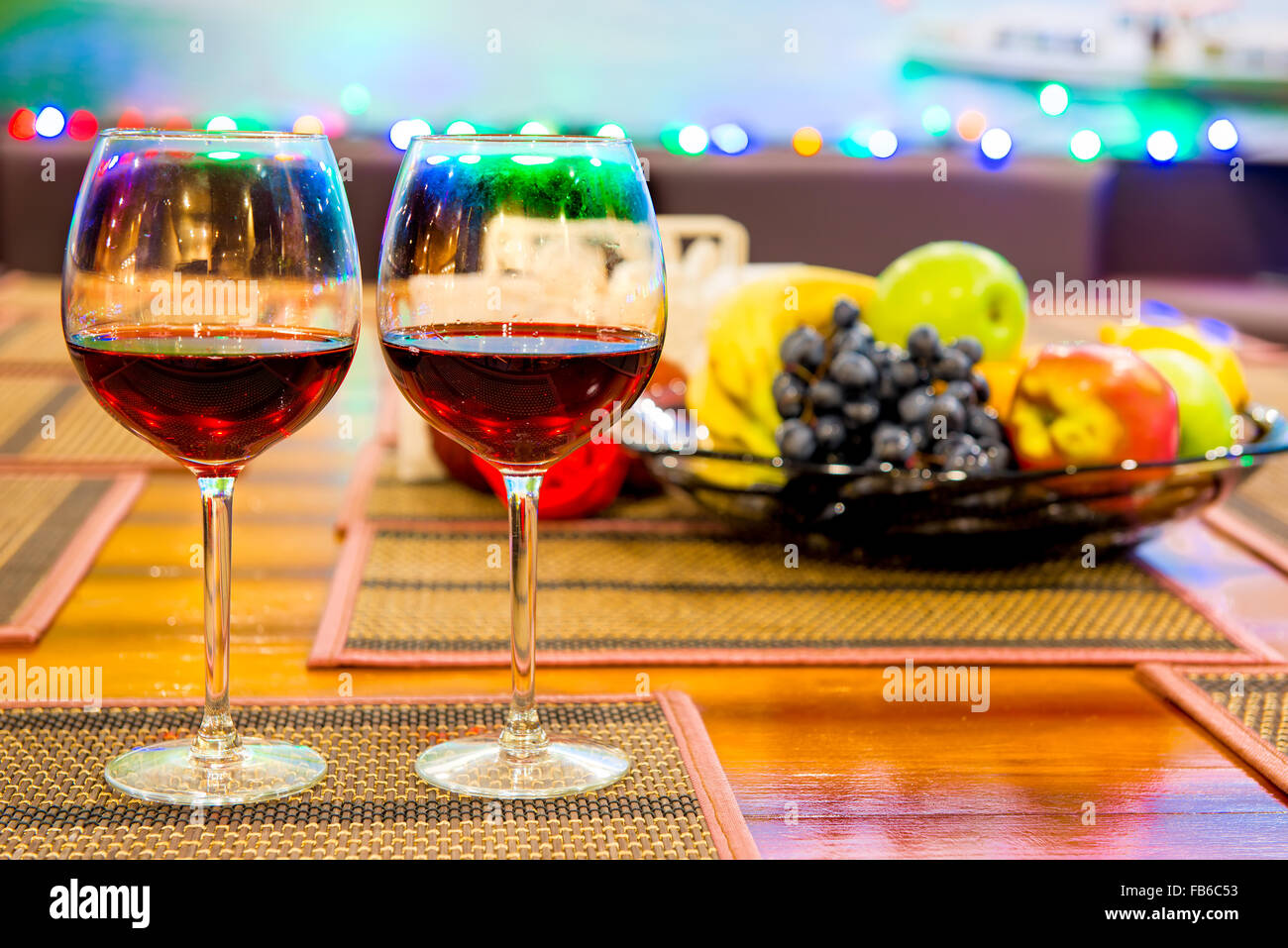 Due bicchieri di vino rosso sul tavolo vicino al vaso con frutta Foto Stock