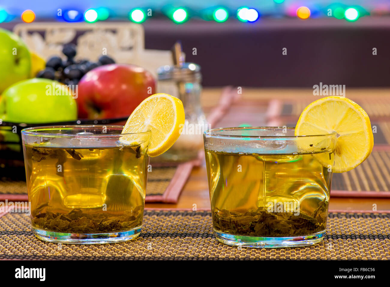 Due tazze di tè verde al limone e frutta sul tavolo Foto Stock