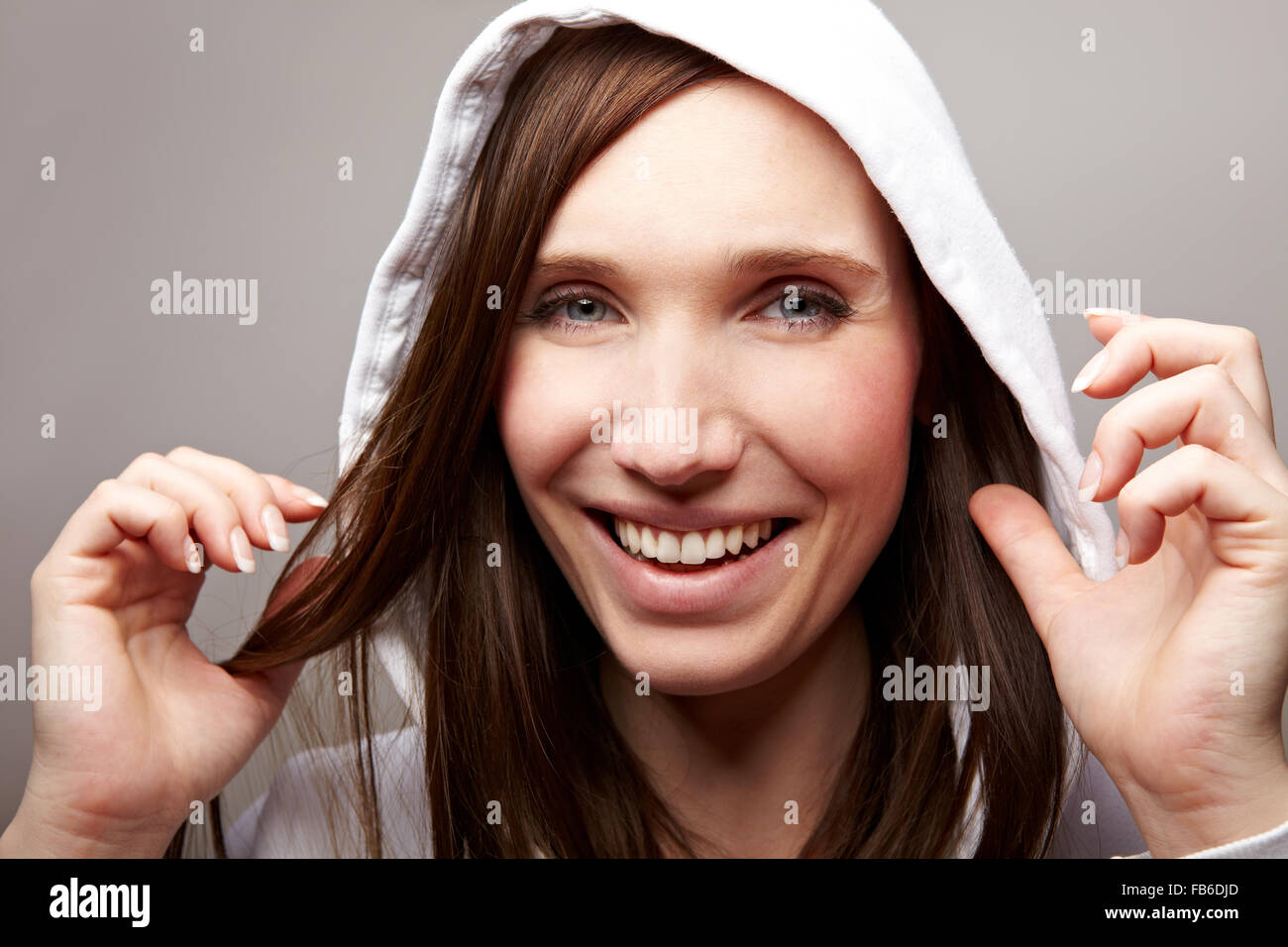 Sorridente giovane donna con felpa con cappuccio sulla sua testa Foto Stock