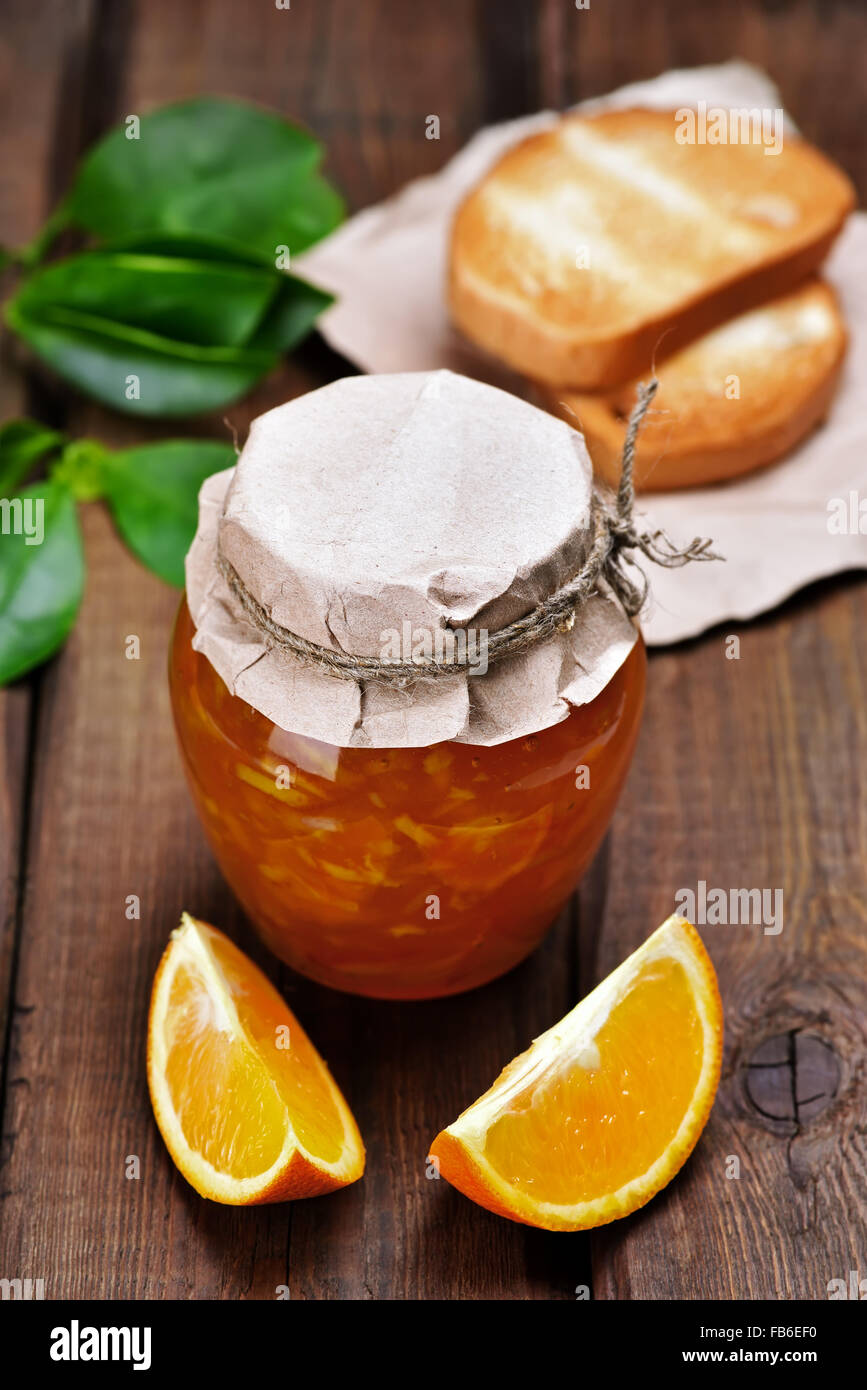 Orange marmellata, fette di pane e sul tavolo di legno Foto Stock