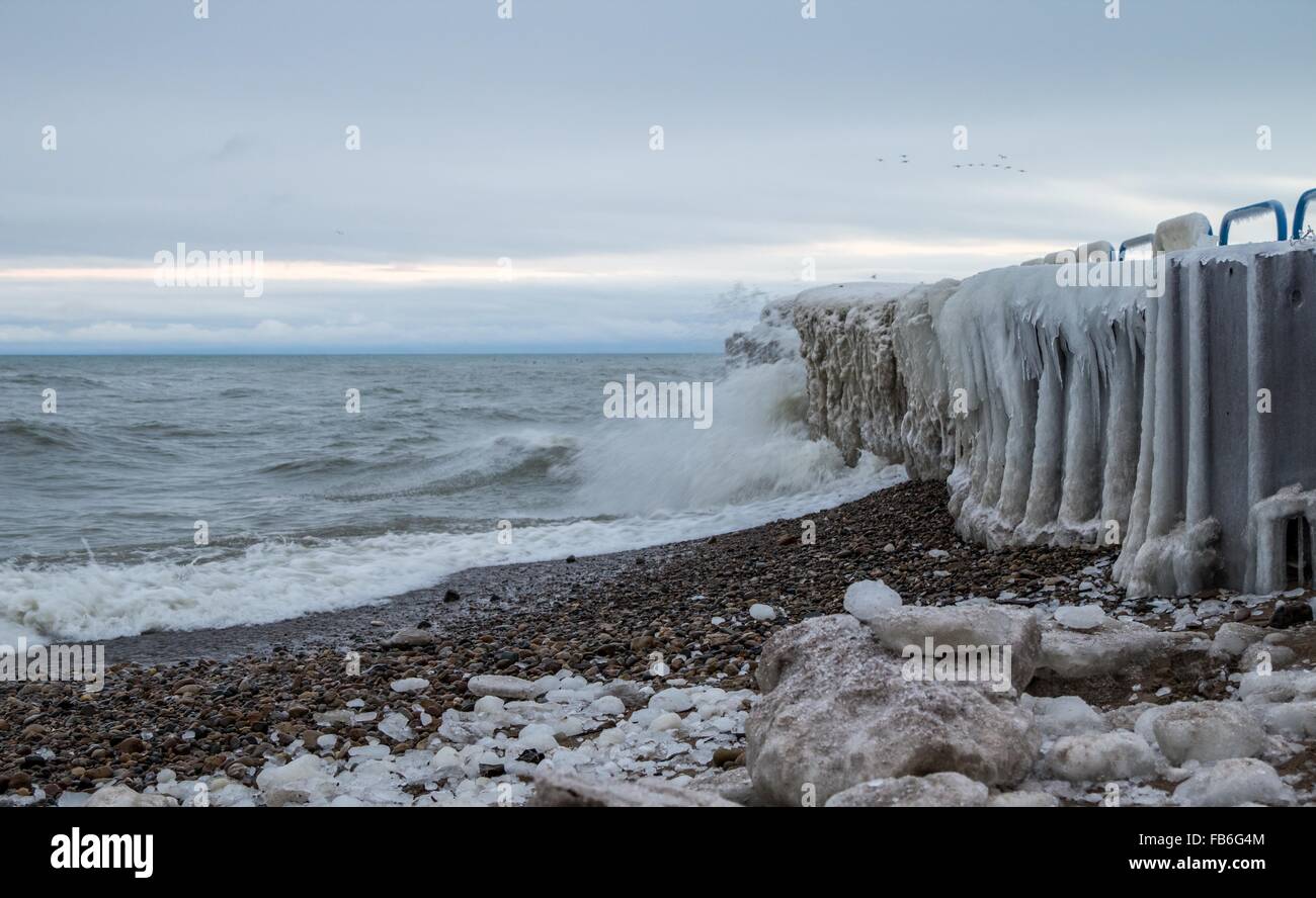 Inverno Seashore paesaggio. Coperte di ghiaccio pier con onde che si infrangono sulla spiaggia sulla costa del Lago Huron. Port Sanilac, Michigan. Foto Stock