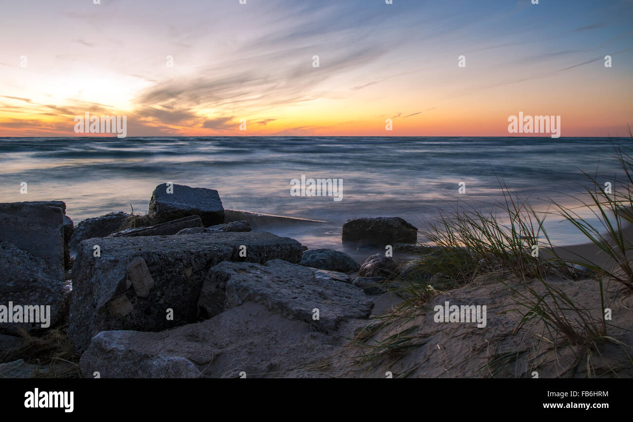 Tramonto sulla spiaggia orizzonte. Il tramonto sulla costa rocciosa di un lago Michigan beach. Ludington parco dello stato. Ludington, Michigan. Foto Stock