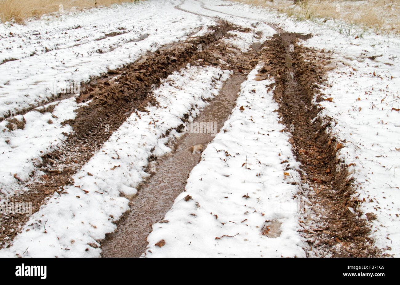 Cattive condizioni della strada: neve, ghiaccio e fango sulla strada di un paese Foto Stock