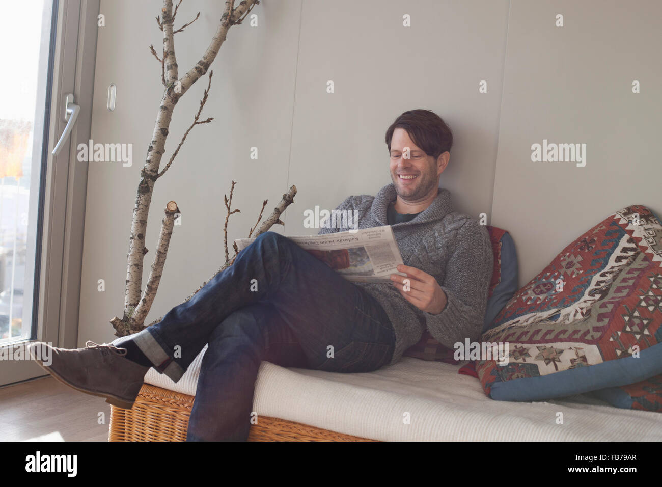 Uomo che legge il giornale in soggiorno Foto Stock