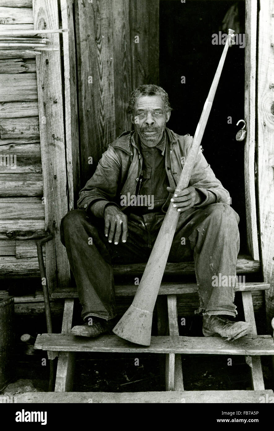 Un 'African American' uomo (ex schiavo) seduta nel vano della porta e tenendo un avvisatore acustico con cui gli schiavi erano chiamati, Texas. Stati Uniti d'America Foto Stock