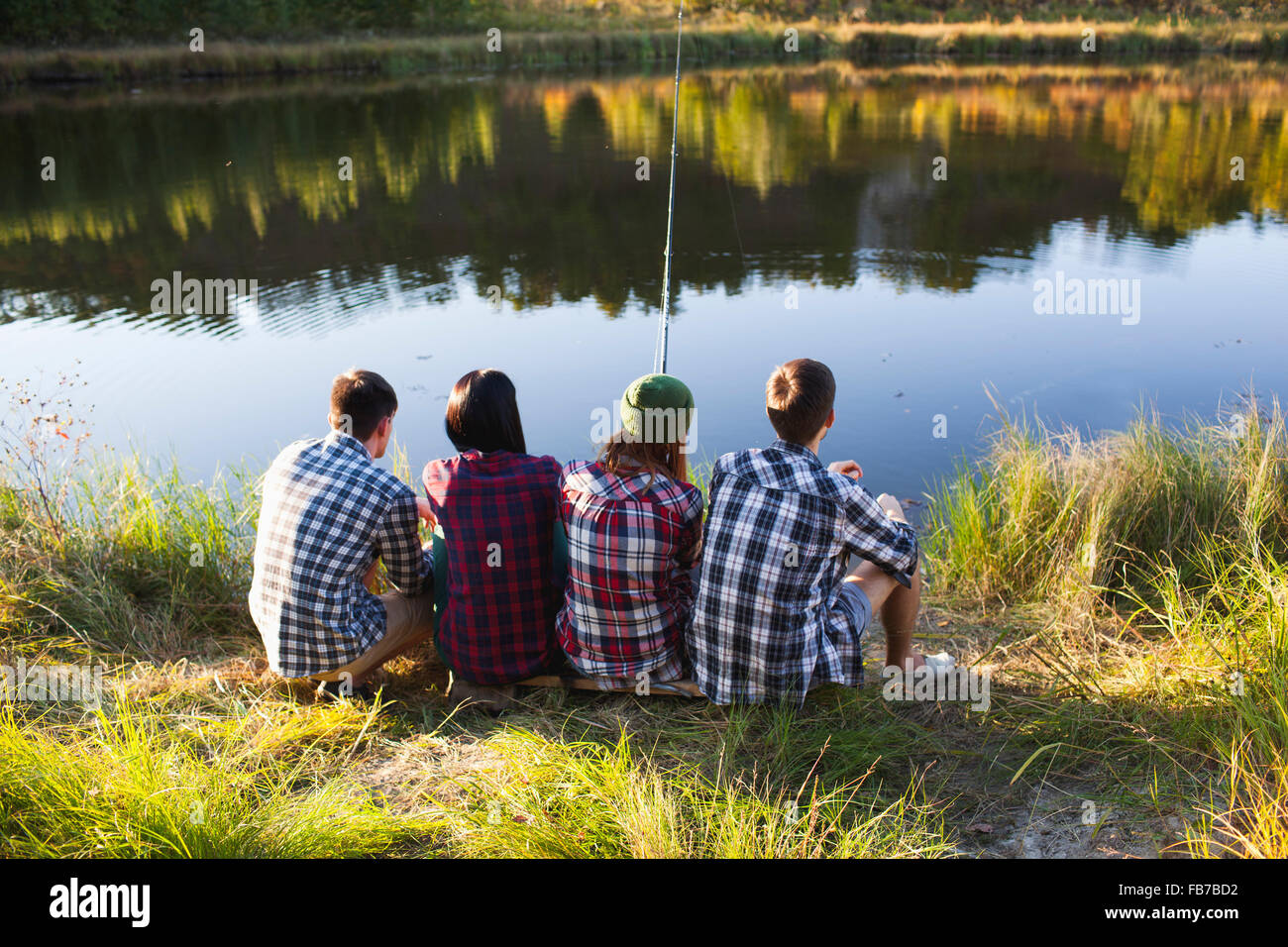 Vista posteriore di amici la pesca sul lungolago Foto Stock