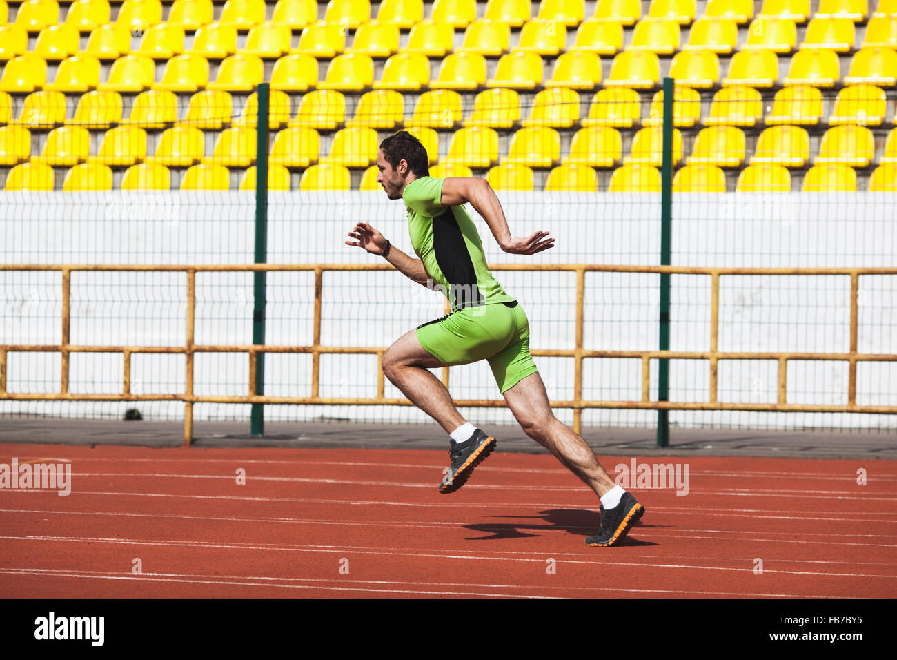 Lunghezza piena vista laterale del giovane sportivo uomo correre sulla pista in stadium Foto Stock