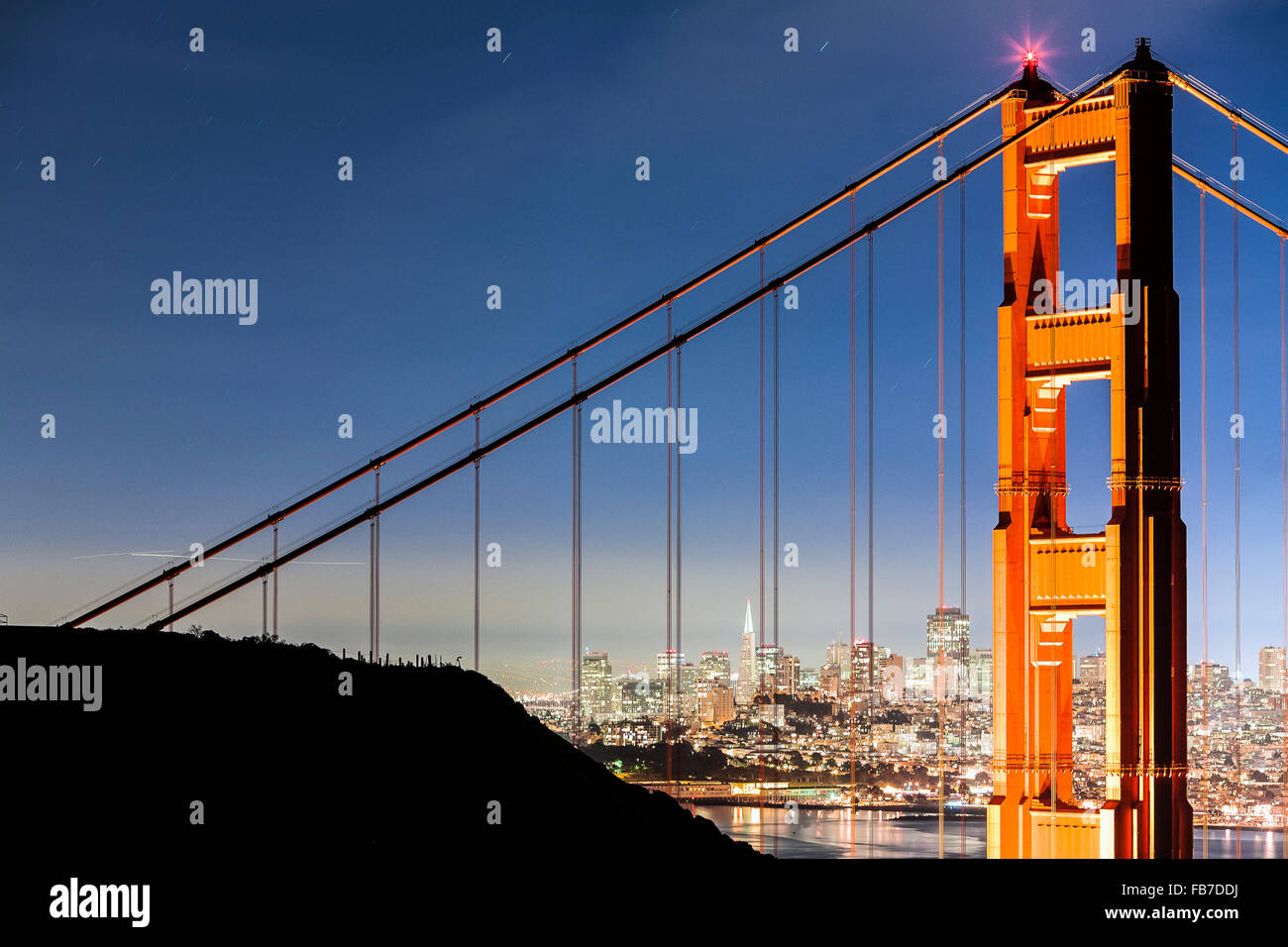 Golden Gate Bridge con paesaggio urbano illuminato in background Foto Stock