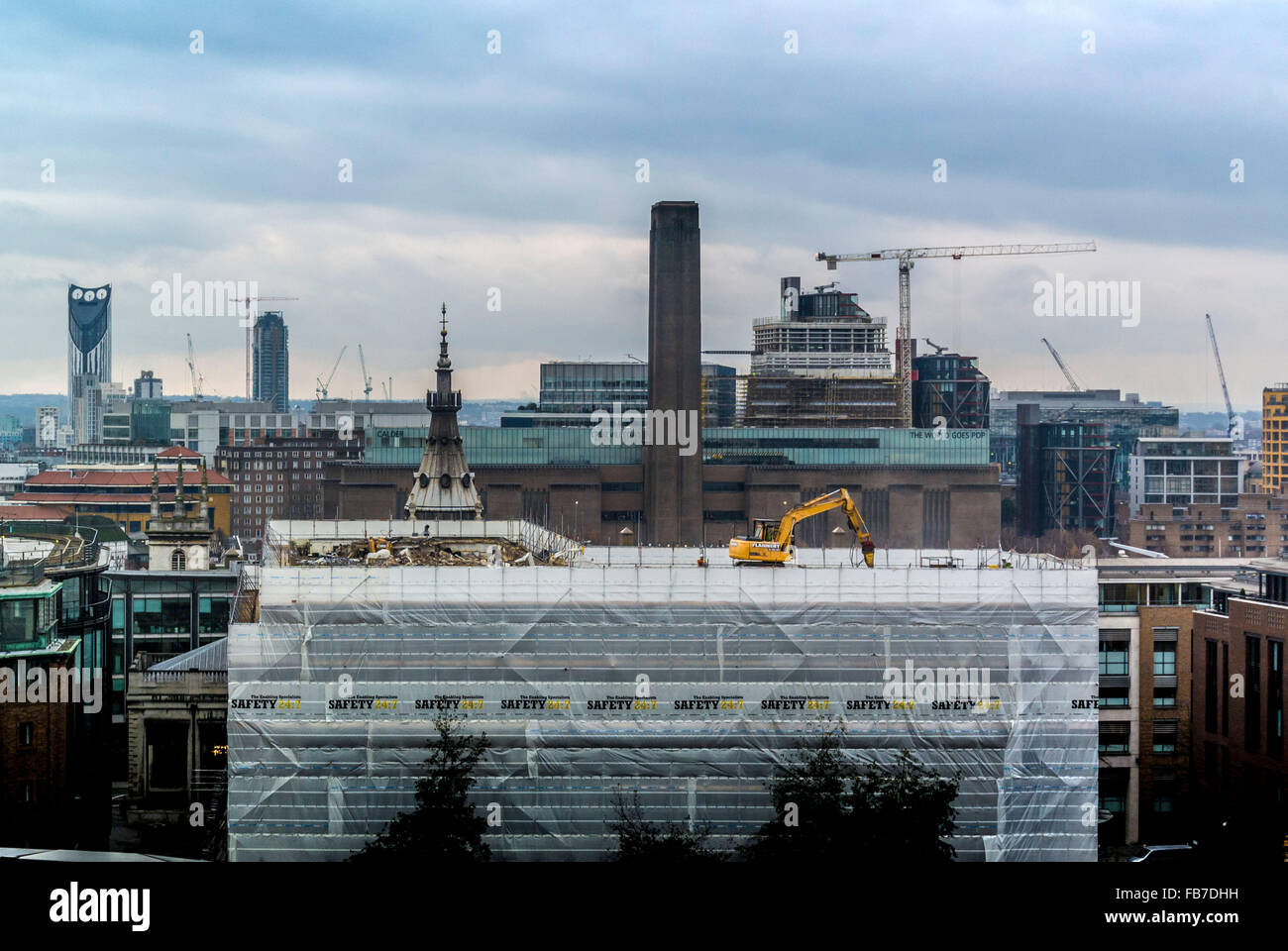 JCB escavatore Digger lavorando sul tetto di un edificio nel centro di Londra Regno Unito con la Tate Modern in background. Foto Stock