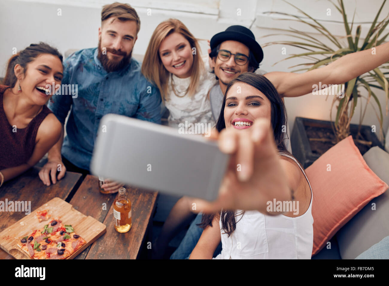 Multirazziale di persone aventi il divertimento a parte prendere un selfie con il telefono cellulare. Un gruppo di giovani amici seduti sul divano tenendo self po Foto Stock