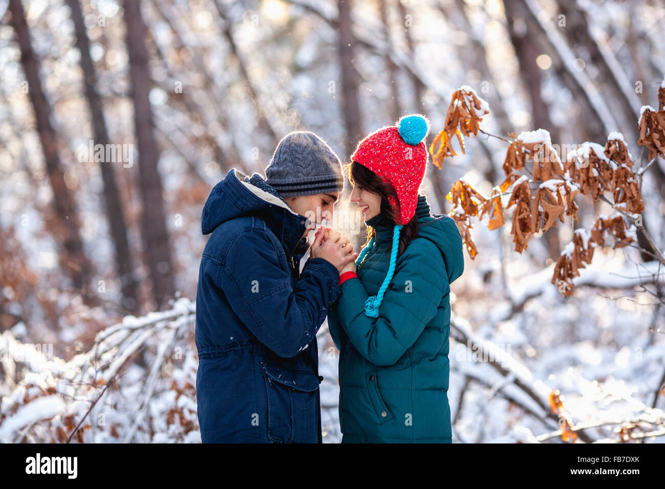 Vista laterale della romantica coppia giovane tenendo le mani durante il periodo invernale Foto Stock