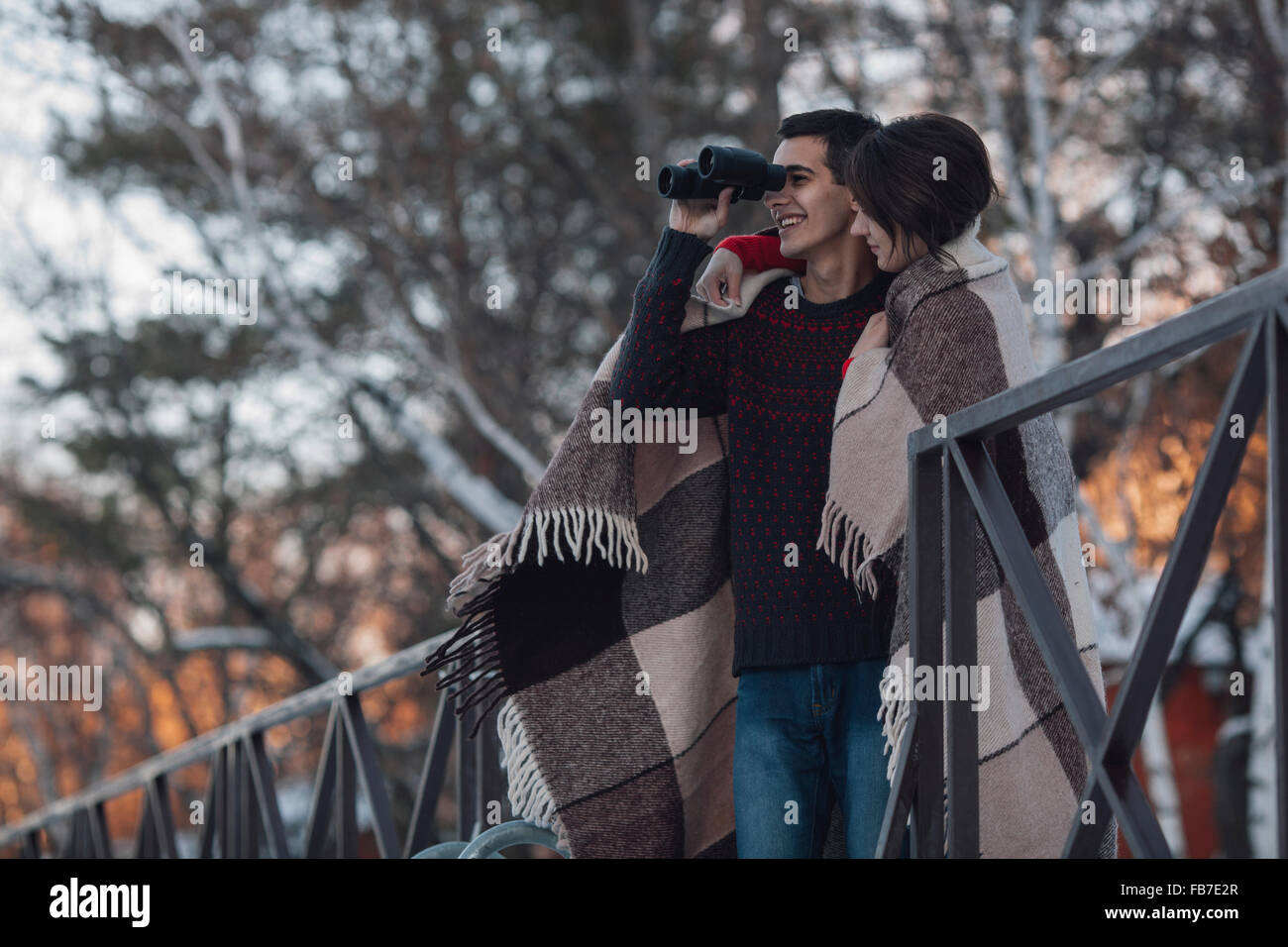 Giovane donna con uomo cerca attraverso il binocolo durante il periodo invernale Foto Stock