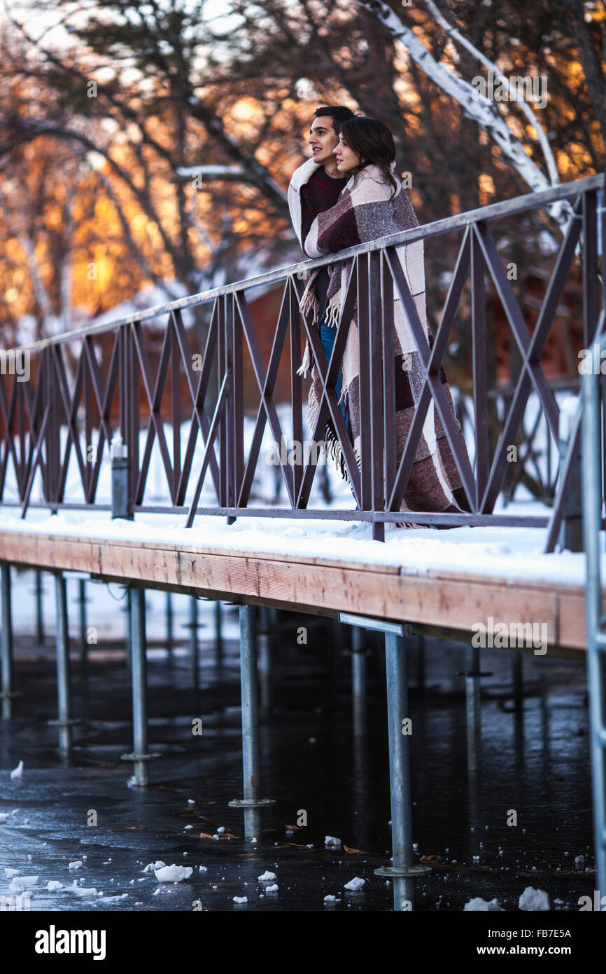 Coppia giovane avvolto in un lenzuolo sul ponte durante il periodo invernale Foto Stock