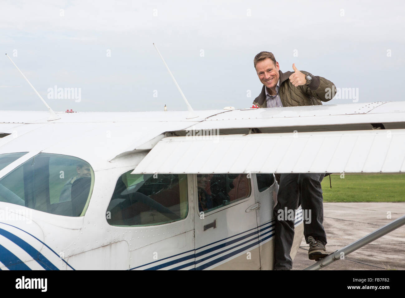 Ritratto di uomo felice gesticolando pollice in su mentre si sta in piedi sul aereo privato contro sky Foto Stock