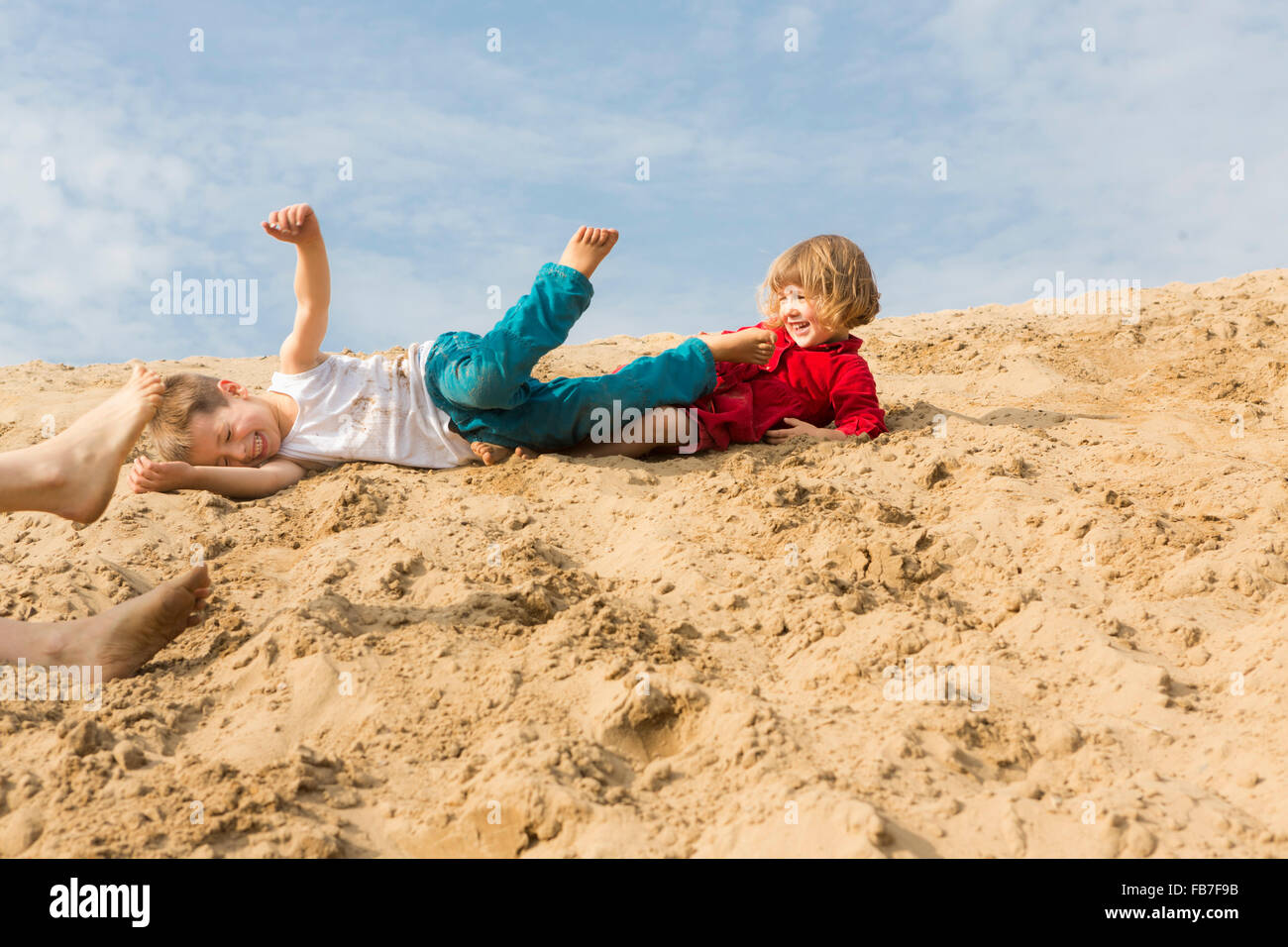 I fratelli godendo sulla duna di sabbia contro sky Foto Stock