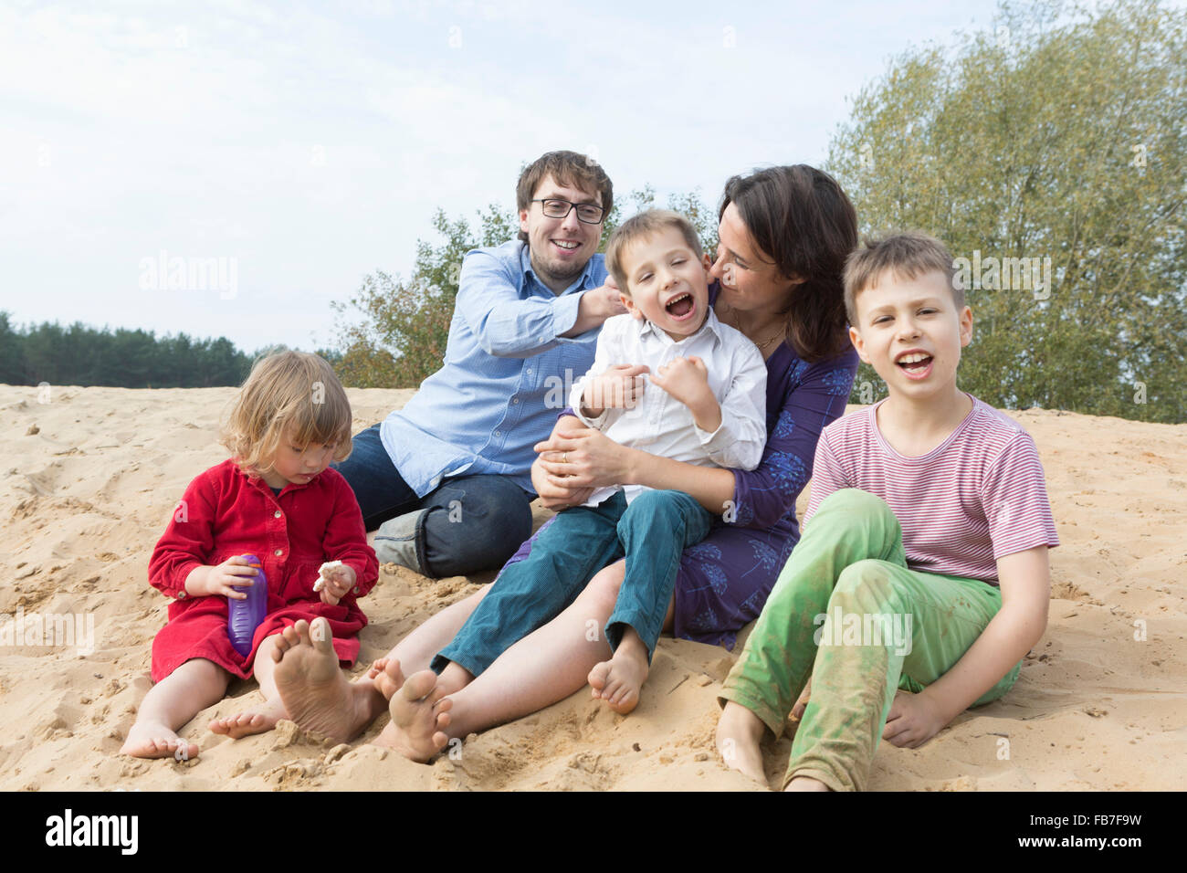 Famiglia allegra seduti insieme sulla duna di sabbia Foto Stock