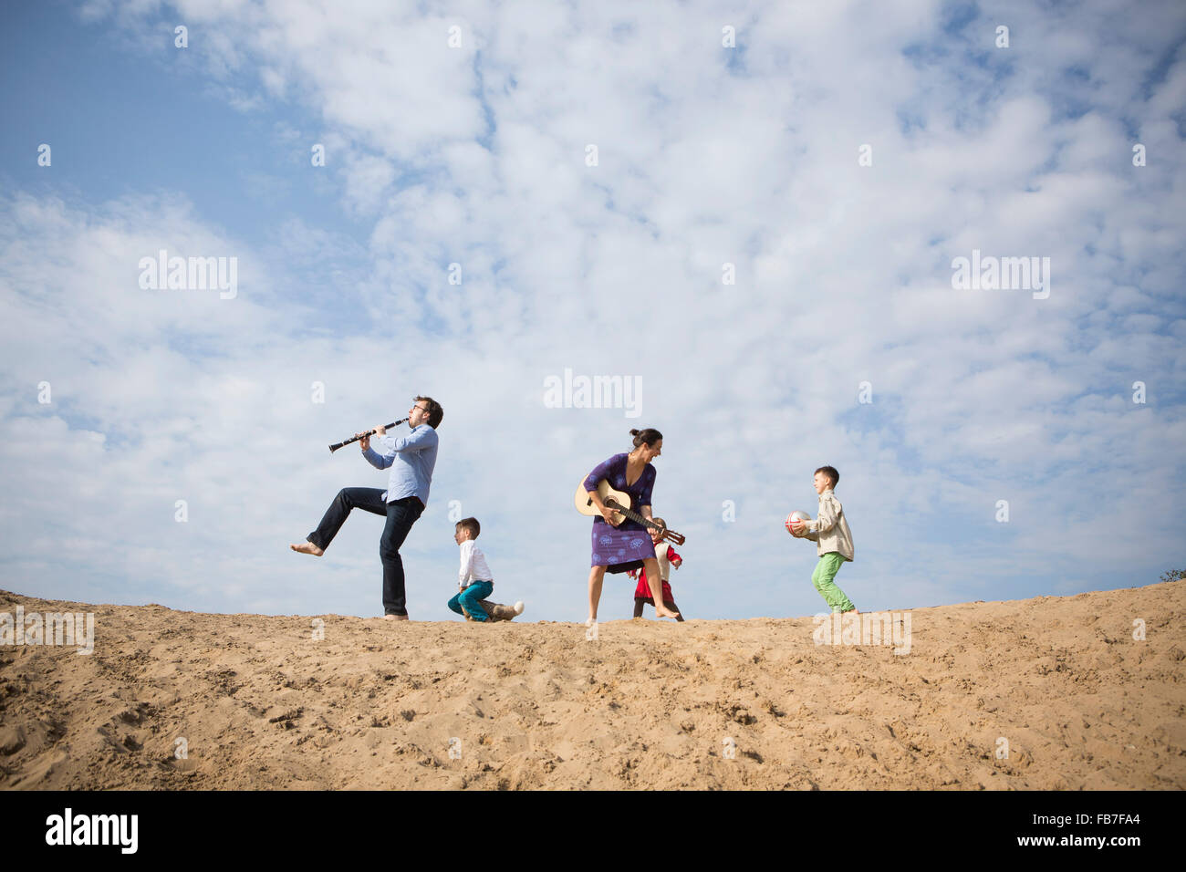 Basso angolo di visione della famiglia godendo sulla duna di sabbia contro il cielo nuvoloso Foto Stock