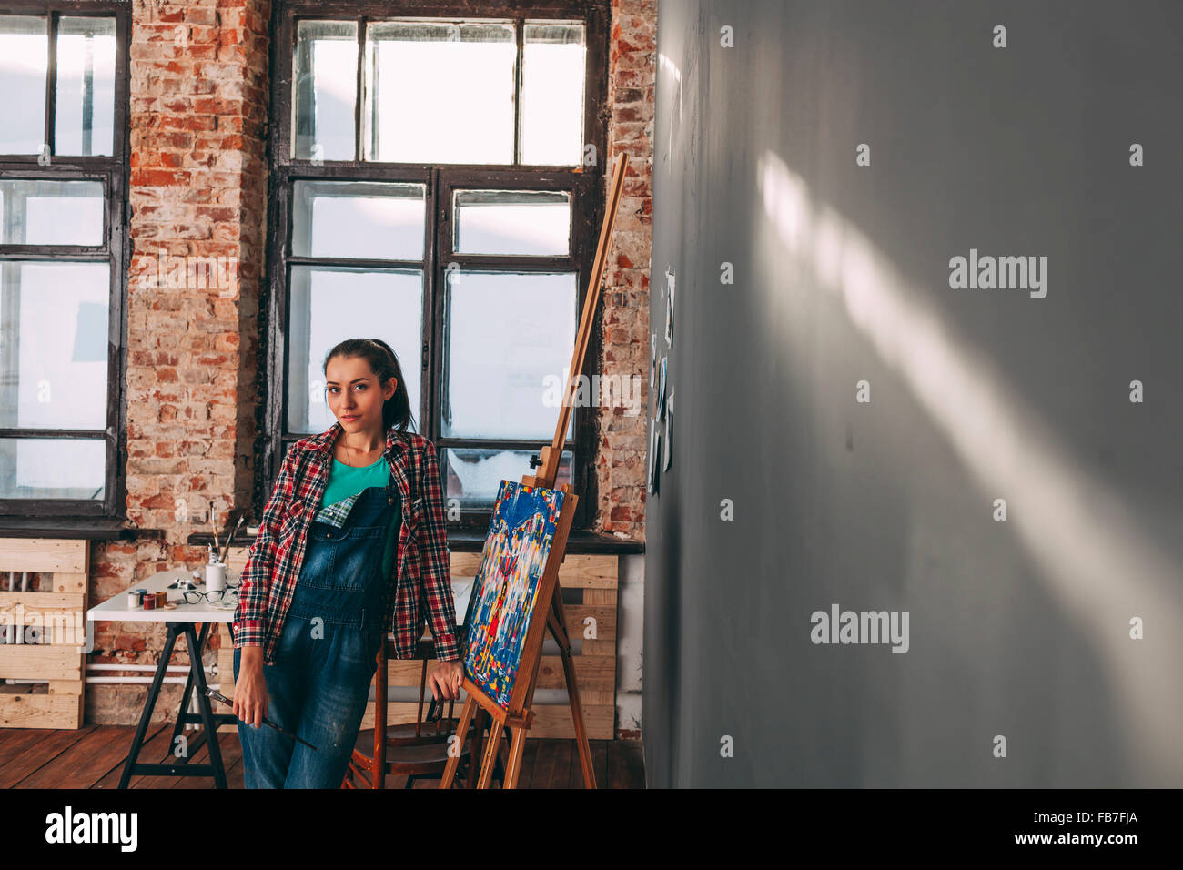 Ritratto di fiducioso pittore femmina in piedi dalla tela in studio Foto Stock