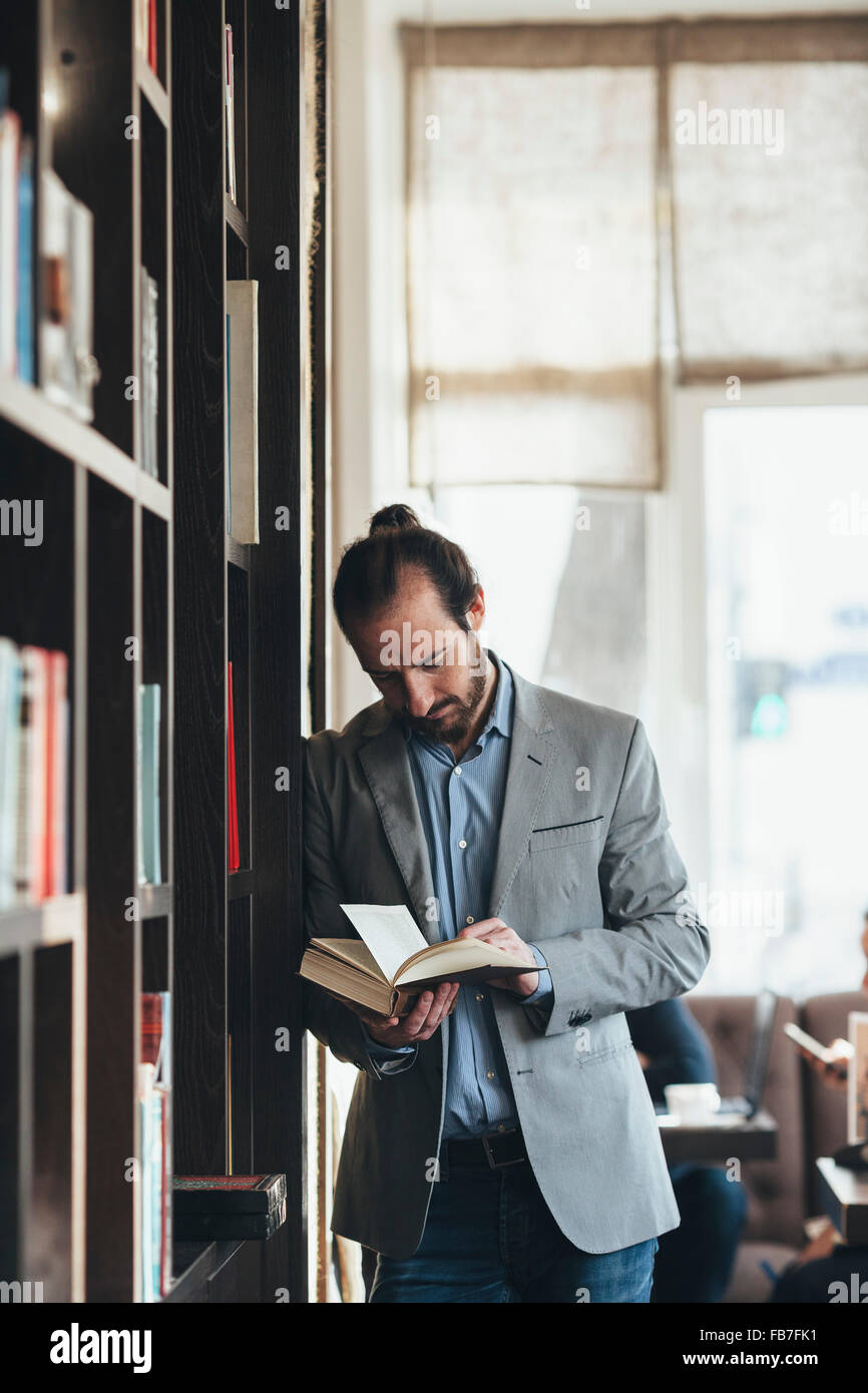 Adulto medio imprenditore libro lettura in cafe Foto Stock