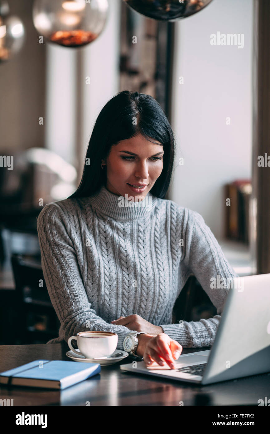 Giovane imprenditrice utilizzando laptop a tavola in coffee shop Foto Stock