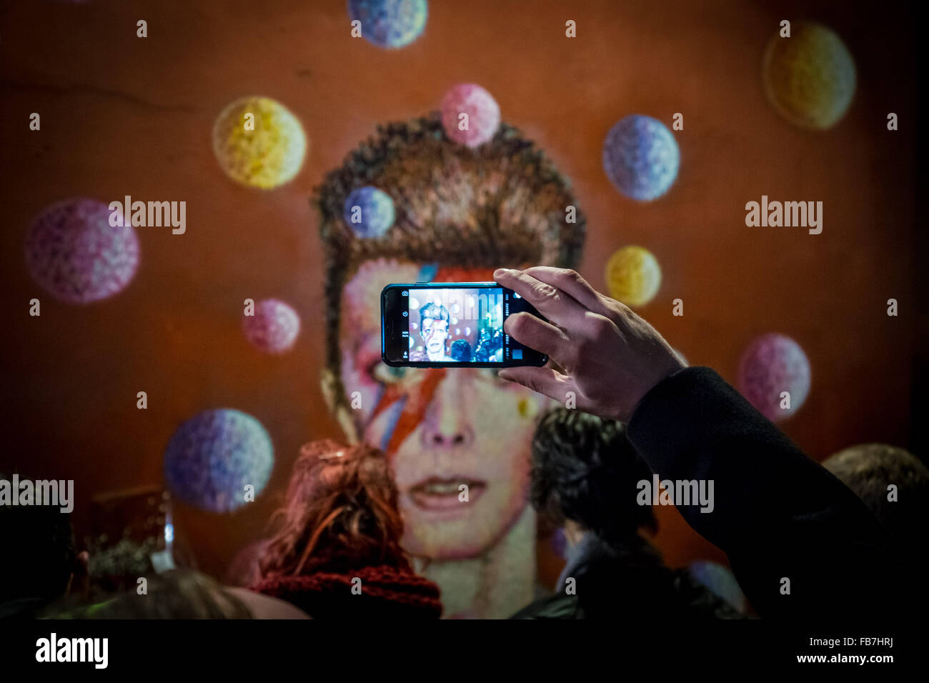 Londra, Regno Unito. 11 gennaio, 2016. Tifosi si riuniscono a David Bowie murale di Brixton, Sud Londra per una serata ricordo veglia, stabilire i fiori e lasciare messaggi. David Bowie (1947-2016) scomparso il 10 gennaio 2016 Credit: Guy Corbishley/Alamy Live News Foto Stock