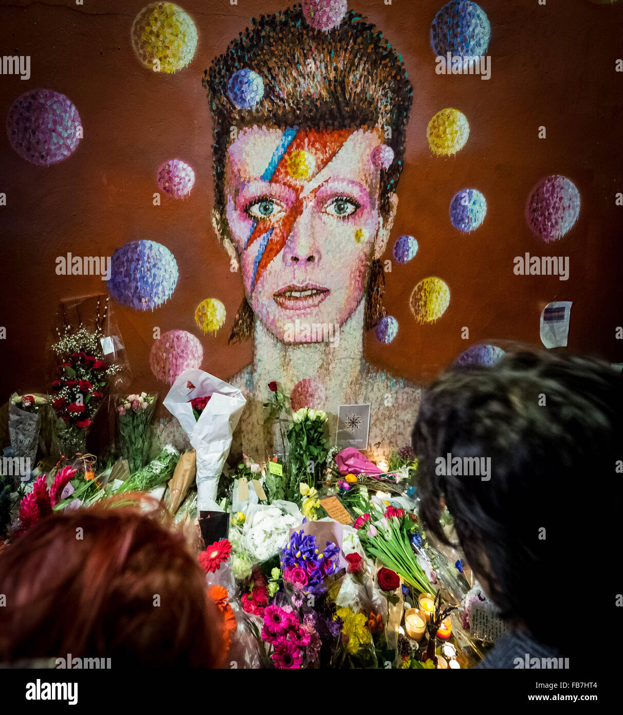 Londra, Regno Unito. 11 gennaio, 2016. Tifosi si riuniscono a David Bowie murale di Brixton, Sud Londra per una serata ricordo veglia, stabilire i fiori e lasciare messaggi. David Bowie (1947-2016) scomparso il 10 gennaio 2016 Credit: Guy Corbishley/Alamy Live News Foto Stock