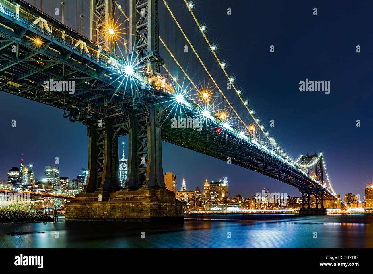 Vista notturna di Manhattan Bridge framing libertà torre attraverso i pilastri del sud Foto Stock
