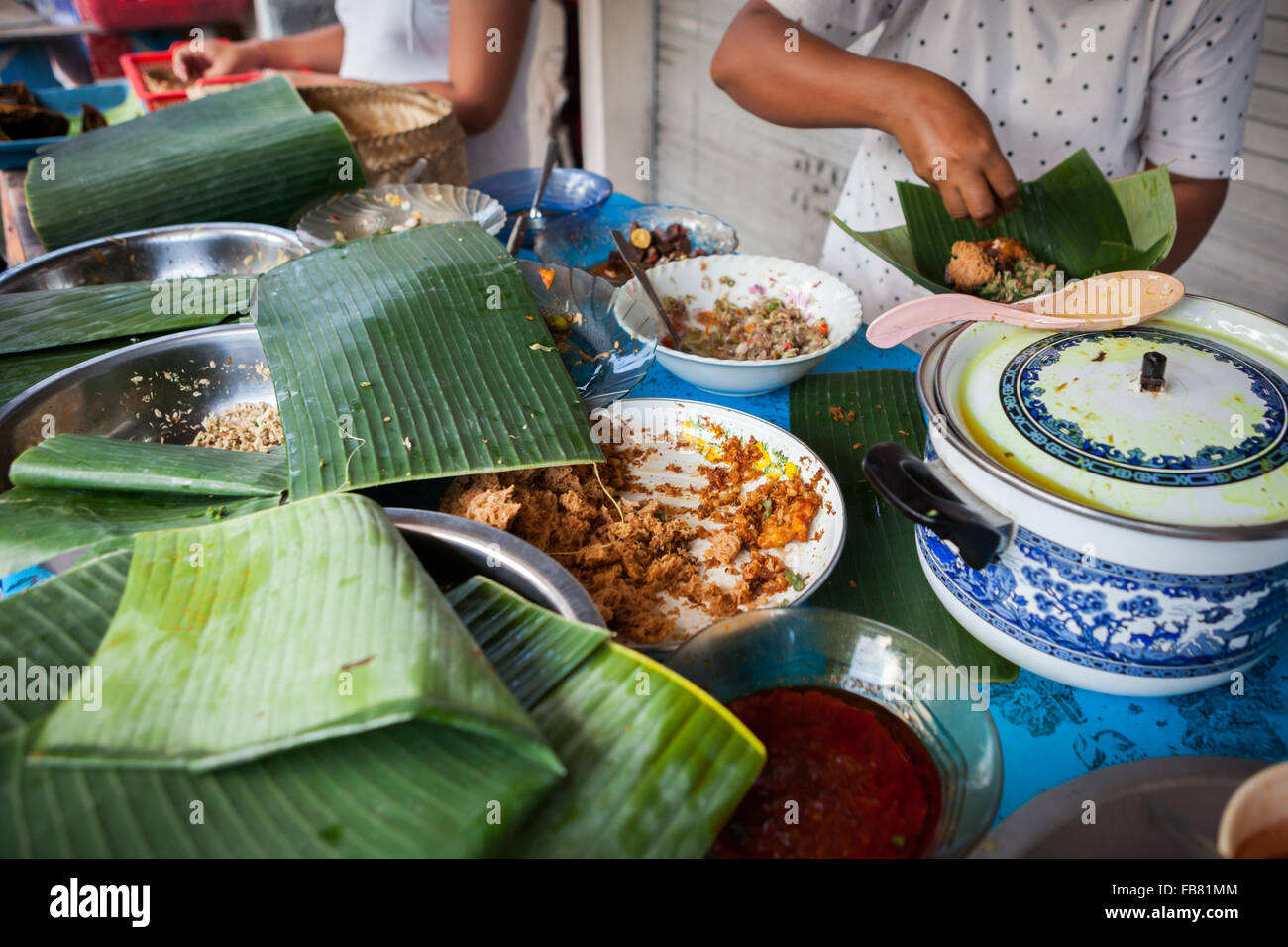 Una donna che serve i clienti in un fornitore di cibo di strada che offre cibo tradizionalmente cucinato a Klungkung, Bali, Indonesia. Foto Stock