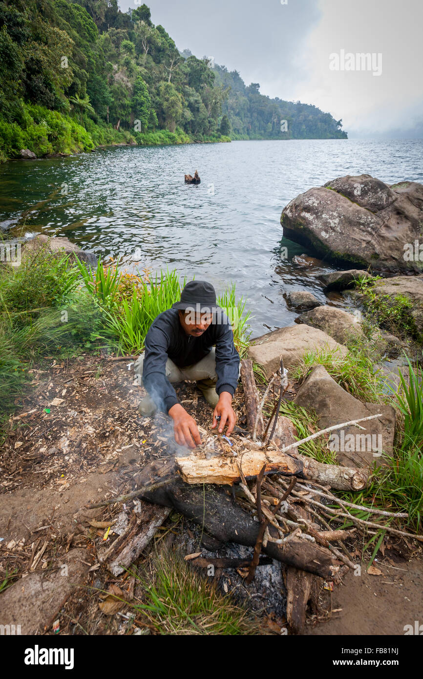 Un ranger che fa fuoco sul lato del lago di Gunung Tujuh in Gunung Tujuh, Kerinci, Jambi, Indonesia. Foto Stock