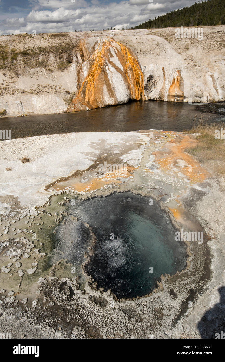 Ebollizione, gorgogliamento di acqua in una primavera calda, con flussi di arancione e il blu del cielo, il Parco Nazionale di Yellowstone, Wyoming. Foto Stock