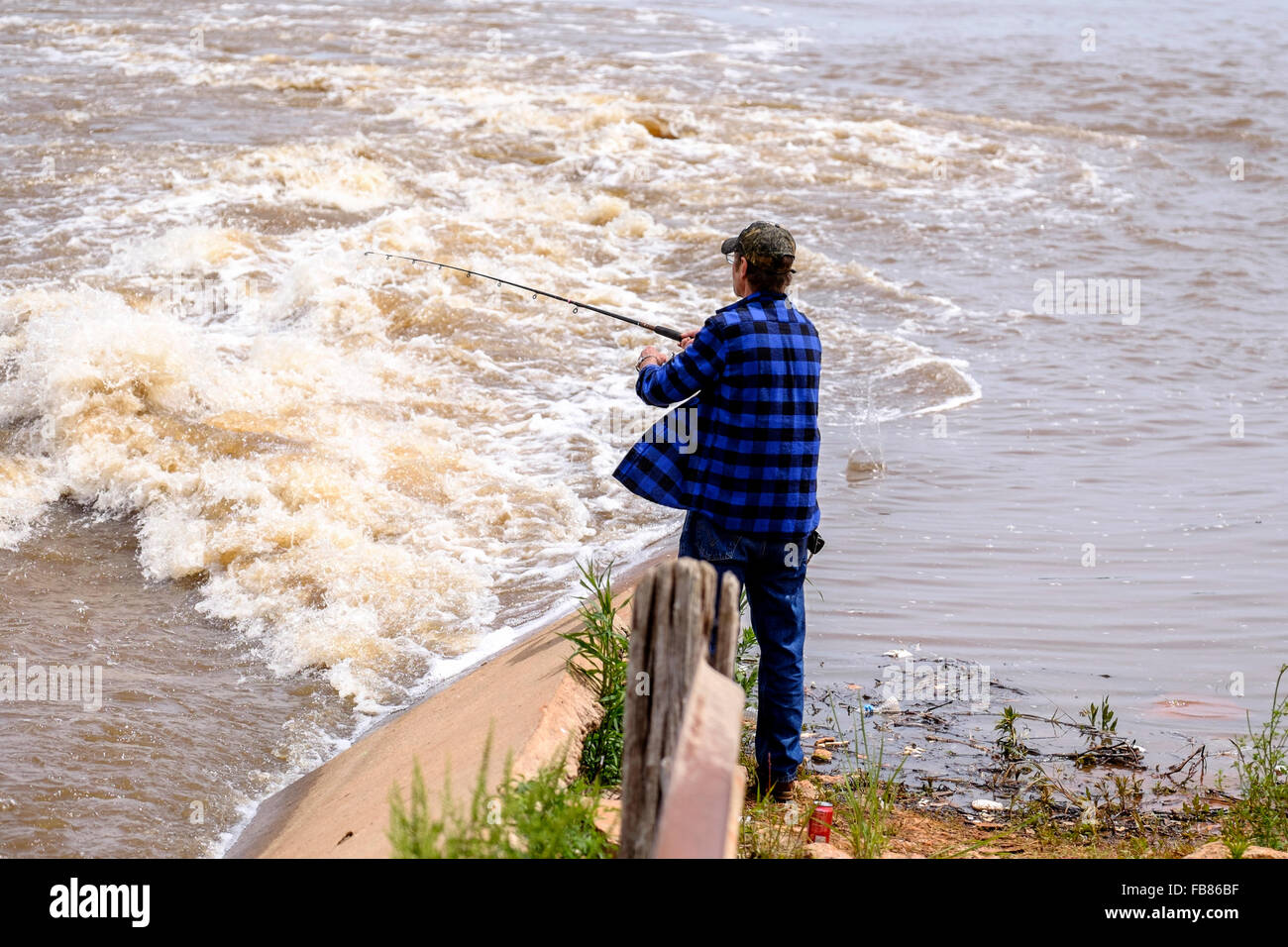 Un uomo pesci nell'innalzamento del livello delle acque del lago Hefner in Oklahoma City dopo una pioggia di primavera. Stati Uniti d'America. Foto Stock
