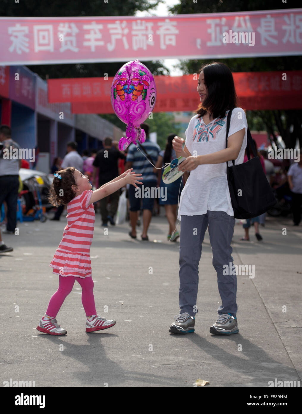 Un misto di gara bimbo e sua madre cinese a una fiera commerciale in una città in Cina. Foto Stock